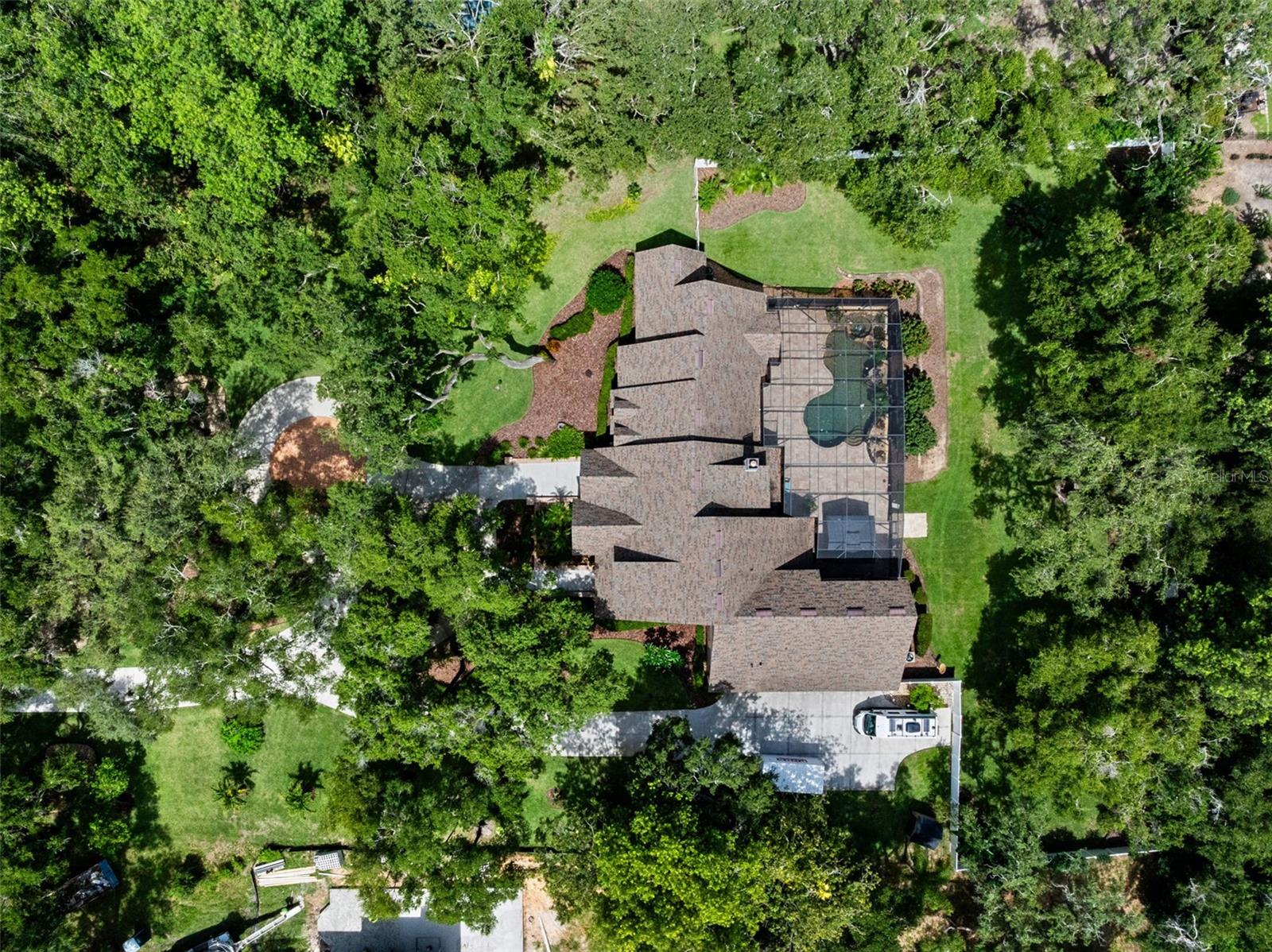 Nestled across a rare double lot among towering cypress and moss-draped trees, this extraordinary modern Tudor estate offers a lifestyle of rare beauty and effortless elegance. Nestled in the exclusive Lake Louisa Oaks community—where lakefront living meets timeless design—this custom-built retreat spans over 5,800 square feet of refined living space.
A long, wooded, recently repaved driveway leads to a stately brick façade that opens into a dramatic two-story foyer with honed travertine floors and a spiraling wood staircase that feels like a work of art. Every detail has been thoughtfully crafted—from rich oak trim to natural stone finishes—creating an atmosphere both warm and elevated.
The main level features a serene primary suite, a chef’s kitchen with generous prep and gathering space, a second bedroom suite, spacious laundry room, and inviting living areas—all with sweeping views of the terraced travertine pool deck, complete with rock waterfall, spa, and privately fenced backyard with lush landscaping. Upstairs, three additional bedroom suites, a media room, and spa-inspired baths ensure comfort and privacy for all.
Outdoors, the resort-style design continues with ample entertaining space surrounded by tropical greenery and sculpted stone. Whether hosting under the stars or enjoying a quiet morning by the water, this home was built for both celebration and serenity.
As a resident of Lake Louisa Oaks, you’ll enjoy access to the coveted Clermont Chain of Lakes via private boat ramp and dock on Lake Louisa, the largest of eleven lakes on the chain, along with park-like amenities including a playground, basketball court, and picnic area. The community’s prime location offers the perfect blend of nature, privacy, and proximity—just west of Orlando’s renowned attractions.
Additional highlights include a whole-house generator, private well, and maintained systems that provide peace of mind and year-round comfort.
This is more than a home—it’s a lakeside haven where architecture, nature, and lifestyle come together in perfect harmony.