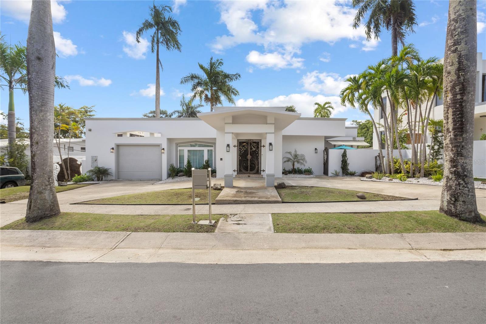 Experience elevated living in Guaynabo’s one and only Garden Hills Norte, where a beautifully remodeled three-level residence blends refined interiors with exceptional outdoor spaces. Designed for those who value elegance, privacy, and effortless entertaining, this 5-bedroom home offers resort-style amenities, lush terraces, and a seamless indoor-outdoor lifestyle.
In the heart of one of Puerto Rico’s most sought-after gated communities, this residence spans approximately 3,859 sq. ft. on a 971 m² lot, offering 4 bathrooms and multiple spaces for both formal gatherings and relaxed family moments.
The main level welcomes you with a gracious foyer leading to formal living and dining rooms, a gourmet kitchen with breakfast area, and a unique champagne room opening to a private terrace—perfect for hosting intimate celebrations.
Upstairs, the expansive primary suite serves as a private retreat with a mahogany walk-in closet, spa-style bathroom, and terrace ideal for morning coffee or evening sunsets. Two additional bedrooms share this level, each with refined finishes.
The lower level is the heart of entertainment, offering a spacious family room with dual sitting areas, a sleek bar, office, gym, and direct access to the covered terrace, pool, and landscaped patio. This seamless indoor-outdoor connection makes it perfect for weekend gatherings, alfresco dining, and enjoying Puerto Rico’s year-round climate.
Equipped with a 30 kW generator, 36 solar panels, and two Tesla batteries, the home delivers comfort and peace of mind. Its prime location offers unmatched convenience to top schools, fine dining, and upscale shopping, making it an ideal choice for executives and high-profile residents seeking the best of Guaynabo living.