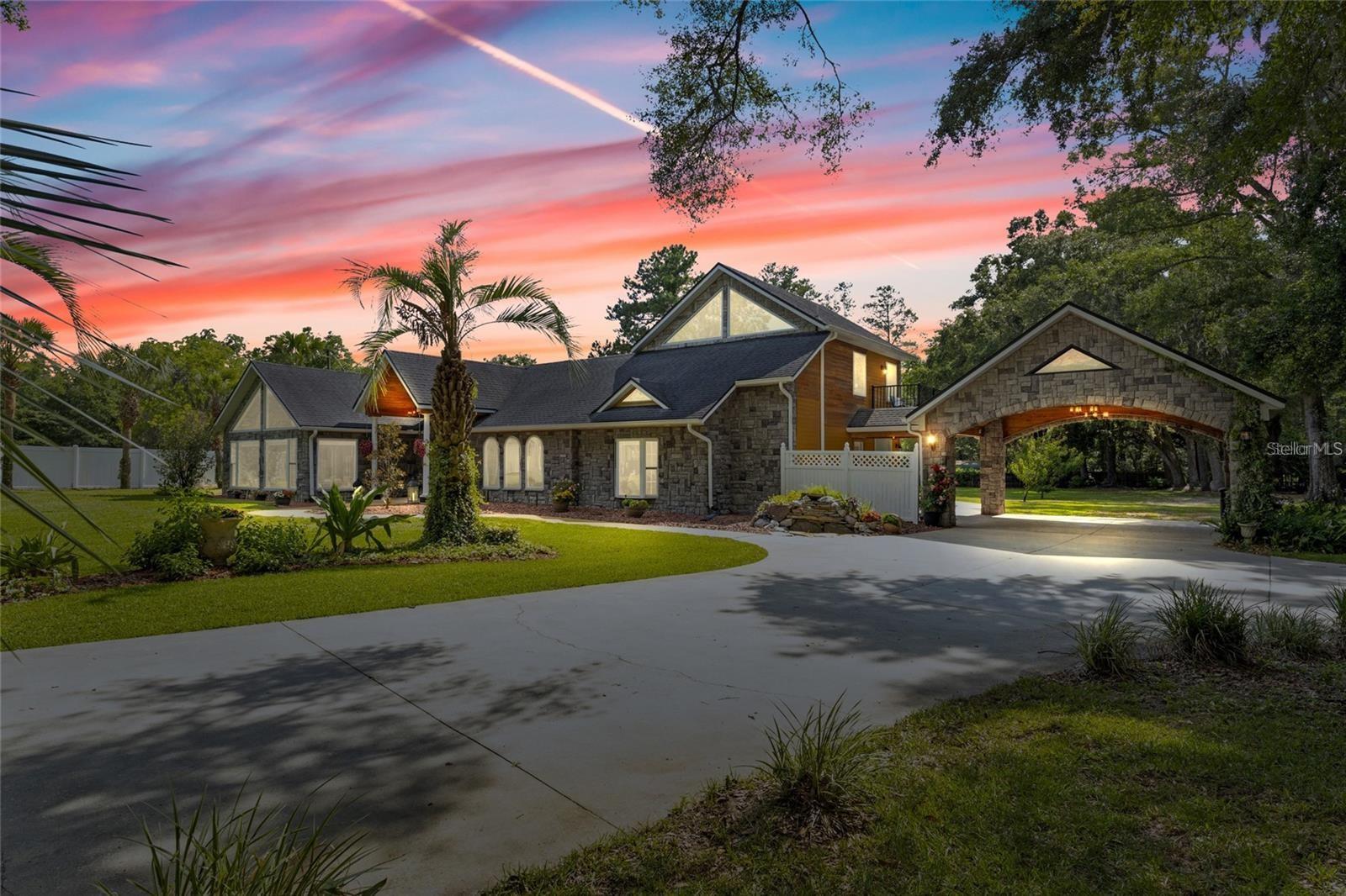 New roof just installed! A GEM in the heart of Lake City, FL, lies a rare treasure: a sprawling estate enveloped by majestic oak and palm trees. At its center stands a magnificent 4,800 sq ft luxury home, meticulously designed with a blend of elegance and functionality that caters to every indulgence. Ideal for relaxation and creating cherished memories in Lake City's tranquil setting. Step inside to discover a sanctuary adorned with opulent features. The interior boasts a seamless fusion of textures and materials—granite, bamboo wood, and marble flooring exude warmth and sophistication under vaulted ceilings crafted from rich cypress wood. Every detail, from the custom-built kitchen to the serene master suite, speaks of artisan craftsmanship and meticulous attention to detail. The gourmet kitchen is a masterpiece in itself, equipped with bespoke all-wood cabinets, exquisite granite countertops, and a suite of high-end appliances that include a 6-burner Viking grill top, dual commercial ovens, a substantial Viking fridge/freezer, and specialized warming and cooling drawers. Ideal for entertaining, the kitchen flows effortlessly into a Florida room framed by top-of-the-line sliding glass doors, offering panoramic views of the lush surroundings. The master suite is a retreat within a retreat, featuring his and hers bathrooms with solid granite floors and countertops, complemented by a custom-built closet system that rivals boutique fashion displays. For guests, a private suite offers a cozy kitchenette with granite accents and a balcony overlooking the verdant landscape. Outside, the allure continues with a pool area designed for relaxation and entertainment, complete with a cooling deck and a patio enhanced by state-of-the-art surround sound and lighting. This home is enveloped in a state of the art Sono's sound system, ensuring music accompanies every moment. Practical amenities abound, including a well-lit carport capable of housing two large vehicles, and a secure paved driveway with automated gate access. The natural beauty of the property is further enhanced by the presence of Rose Creek, meandering gracefully through the rear grounds, offering a serene backdrop of wildlife and tranquility. This estate epitomizes a harmonious blend of luxury and comfort, offering a rare opportunity to immerse oneself in the laid-back elegance of Lake City's countryside while enjoying the finest in modern living.