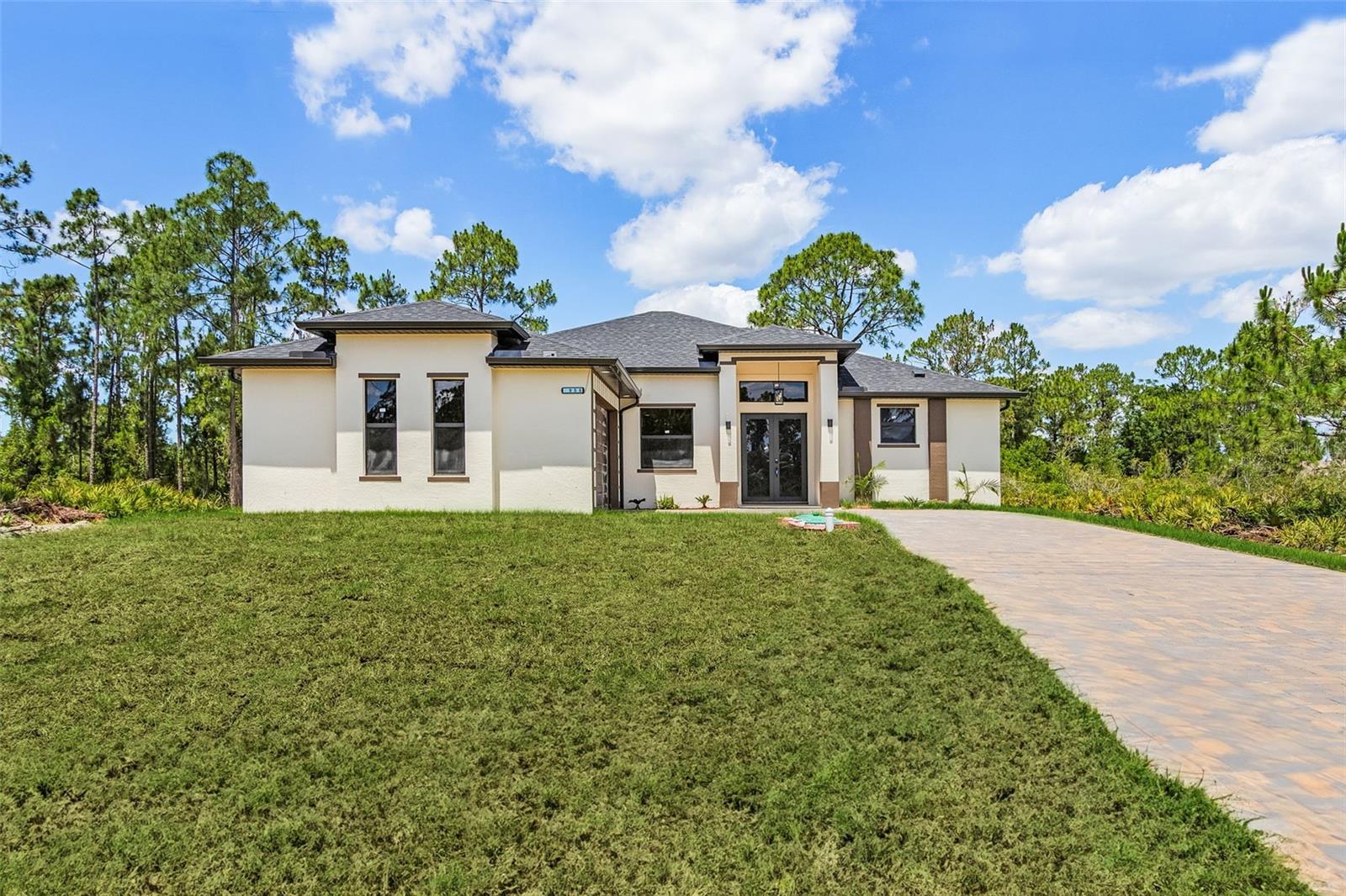 $5,000 COVERED CLOSING COSTS! Welcome to this stunning, elegant retreat in the heart of Lehigh Acres—a custom-designed 3-bedroom, 3-bathroom home + Den that offers 1,906 sq ft of refined living in a quiet and secure neighborhood, just steps from State Road 82, a centrally located, low-traffic route for effortless commuting and convenience. With soaring ceilings, extra-tall doors, and high-impact windows, this home boasts an open, airy atmosphere filled with natural light and thoughtful luxury at every turn. From its modern architecture to its functional layout, every detail has been designed for both sophistication and comfort. Each of the 3 bedrooms is a private suite, complete with its own full bathroom and large walk-in closet, providing privacy and convenience for family and guests alike. One of the bedrooms features its own private entrance to the outside, ideal for guests, in-laws, or a home office setup. Additionally, one of the bathrooms also has direct access to the backyard, making it perfect for entertaining or future poolside use. The primary suite is a true sanctuary, offering a spacious layout and a beautiful, spa-like bathroom designed for relaxation. At the heart of the home is a show-stopping chef's kitchen with marble granite countertops, a range hood, double oven, French-door refrigerator, dishwasher, and a modern workstation sink equipped with a built-in cup washer, veggie washer, and cutting board—a true culinary experience. Wide sliding glass doors lead to a fully tiled terrace where you can unwind, dine, or entertain outdoors while enjoying the Florida breeze. Additional luxury features include: • Expansive paver driveway that fits 6+ vehicles • Oversized two-car garage with storage space • Spacious den, ideal as a home office or flex room • Fully automated sprinkler system for easy lawn care • Designer lighting and energy-efficient finishes throughout • Meticulously landscaped yard with space • Quiet, family-friendly street in a safe, well-maintained neighborhood This home perfectly blends luxury, function, and location—ready to welcome you with comfort and timeless style. Don't miss your chance to experience elevated Florida living.