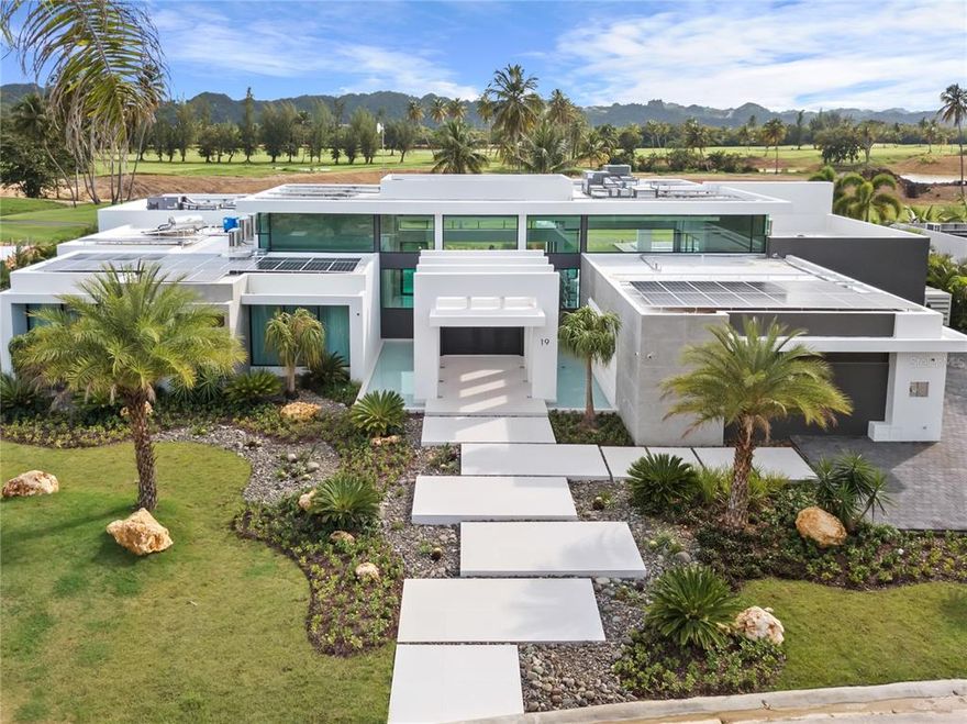 Featured in Architectural Digest Spain and design magazine Modo de Vida, this stunning contemporary home was designed for a lifestyle of leisure. Just steps from the DB Clubhouse, this property has 5 spacious bedrooms, 4 full baths, 2 half baths, and top of the line entertainment facilities, including a heated pool, outdoor bar, wine cellar, and golf simulator.

Premium landscaping features such as dual fountains at the entryway and designer lighting across the yard make this home stand out amongst others in the area. An upgraded driveway leads to a spacious garage with more than enough room for two cars and two golf carts, plus plenty of storage.

The floor plan is designed to maximize views of the nearby golf course and surrounding mountain scenery. With 18” ceilings and floor-to-ceiling windows, the home is filled with natural light.

This home boasts the finest European finishes throughout. Spanish porcelain tile flooring gives a beautiful marble effect with improved durability, and in the kitchen, custom Italian cabinets create a modern minimalist aesthetic, whilst an oversized island with two waterfalls adds a sense of grandeur.

Wine enthusiasts will appreciate the temperature- and humidity-controlled cellar, whilst the Trackman Simulator will appeal to keen golfers. At the rear of the property, this home has a large, heated swimming pool with a sun shelf and spa pool, a gas fire pit, and a full-sized outdoor bar with an 85” TV and luxury grill. 

No expense has been spared to future-proof this home, with custom-programmed Vitrea light switches, top of the range sound system, and ACMaster installed throughout the home. 100 40kw solar panels have been installed on the roof, with a 13.5kwh Tesla Powerwall and backup generator to provide almost a week’s worth of power.
