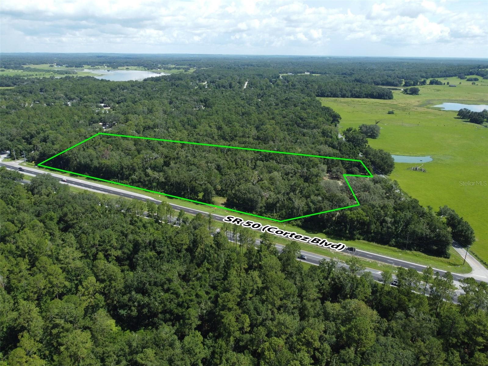 Outstanding commercial development opportunity along one of Hernando County’s most traveled corridors. This 11.90-acre parcel features approximately 826 feet of frontage on Cortez Boulevard (State Road 50), with an Average Annual Daily Traffic (AADT) count of 29,500 vehicles per day. Zoned C1 at the front and AG at the rear, the property is ideally suited for a wide range of commercial applications—retail, fast-casual or quick-service dining, medical, office, or mixed-use development—subject to county approval. A conceptual site plan has been prepared by PROCIVIL 360, providing a strong foundation for development. Water service is conveniently available from WPA Road. As is typical for this market, municipal sewer service is not available; however, septic systems are widely accepted and utilized throughout the area, making this a practical and feasible option for new development. Located just minutes from the Historic City of Brooksville, this site combines modern development potential with small-town charm. Brooksville is known for its tree-lined streets, preserved architecture, and vibrant downtown—hosting seasonal festivals, farmers markets, and a growing local business scene. This blend of historic character and forward-looking growth has made the area increasingly attractive to both residents and commercial developers. The property is strategically positioned between two major transportation arteries—just 5 miles from Interstate 75 and 10 miles from the Suncoast Parkway—offering exceptional regional connectivity. It is also 12 miles from the Brooksville–Tampa Bay Regional Airport and 50 miles from Tampa International Airport. Downtown Tampa is 45 miles away, while Clearwater Beach, St. Petersburg, and Orlando are all within 63 to 70 miles—placing the site within reach of four major metropolitan areas. For national retailers, commercial builders, and investors seeking visibility, flexibility, and long-term upside in a high-growth corridor, this is a rare and compelling opportunity.