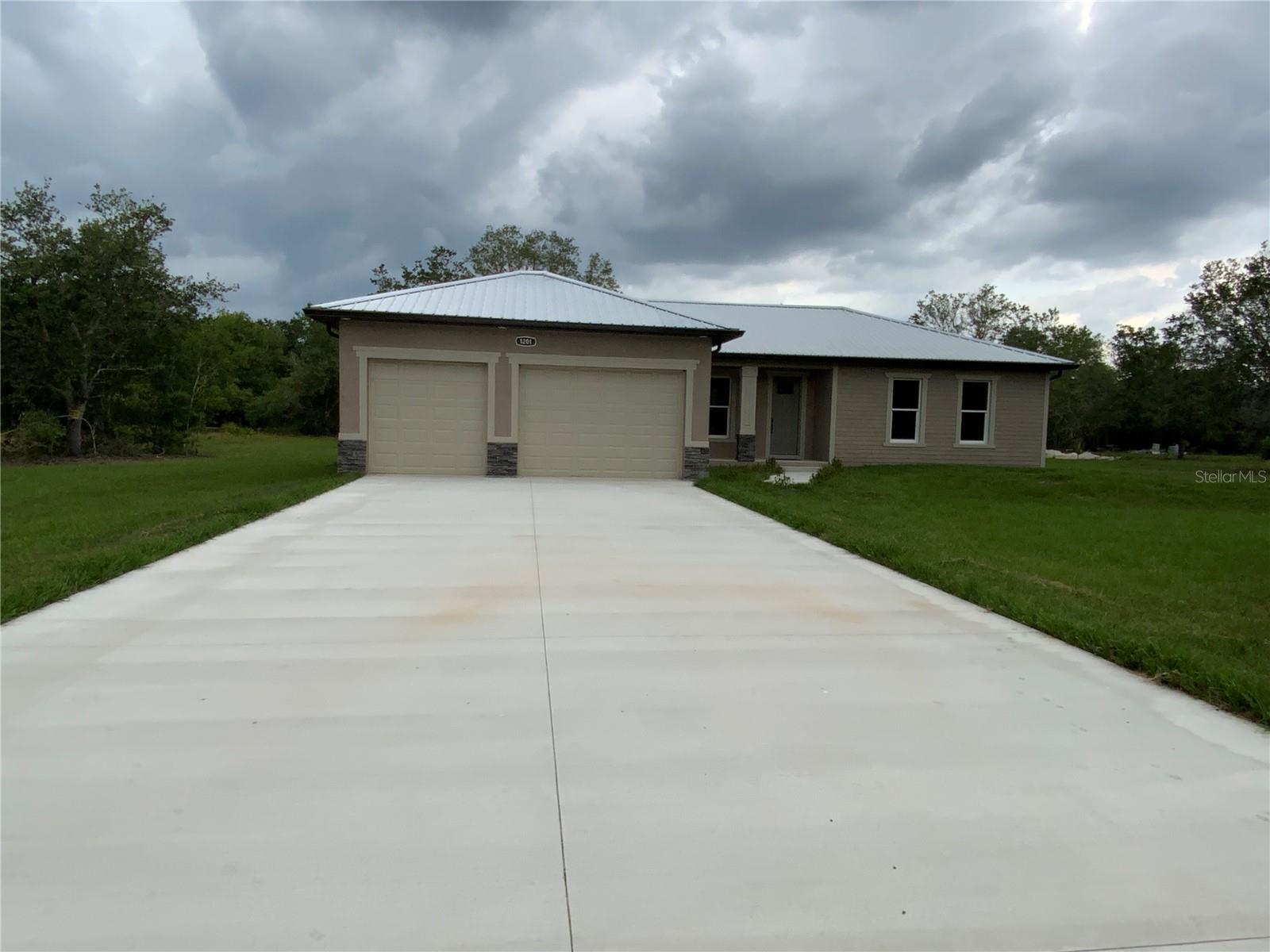 Custom-built three bedroom, two bath, extra room, three car garage new home featuring all the luxurious amenities you can imagine. On over 1.25 acres. The owner spared no expense in creating this tastefully finished residence. From the moment you pull in, you'll appreciate the beautiful curb appeal, highlighted by attractive stonework. A convenient garage accommodates 2 to 3 cars and a fabulous front porch seating area. As you open the eight-foot front door, you'll be amazed by the coffered and tray ceiling finishes, gorgeous tile work, and all-quartz countertops. The 10-foot ceilings throughout create a spacious and upscale atmosphere. The open floor concept makes entertaining a pleasure; if you need more space, slide open the stunning doors to enjoy the breeze on the expansive porch while taking in views of the large backyard. The kitchen is a chef's dream, featuring ample cabinetry, a fantastic serving/breakfast island, and a large hidden walk-in pantry. The main bedroom and bathroom are equally impressive, with beautiful tray ceilings, huge walk-in closets, and his-and-her sinks. Situated over an acre of land, there's plenty of room for parking boats and RVs, making it an ideal setting for a custom pool and charming barn. Seller may consider short-term seller Financing with $150,000 down. Also, the adjacent 1.25 acres may be available for additional cost.