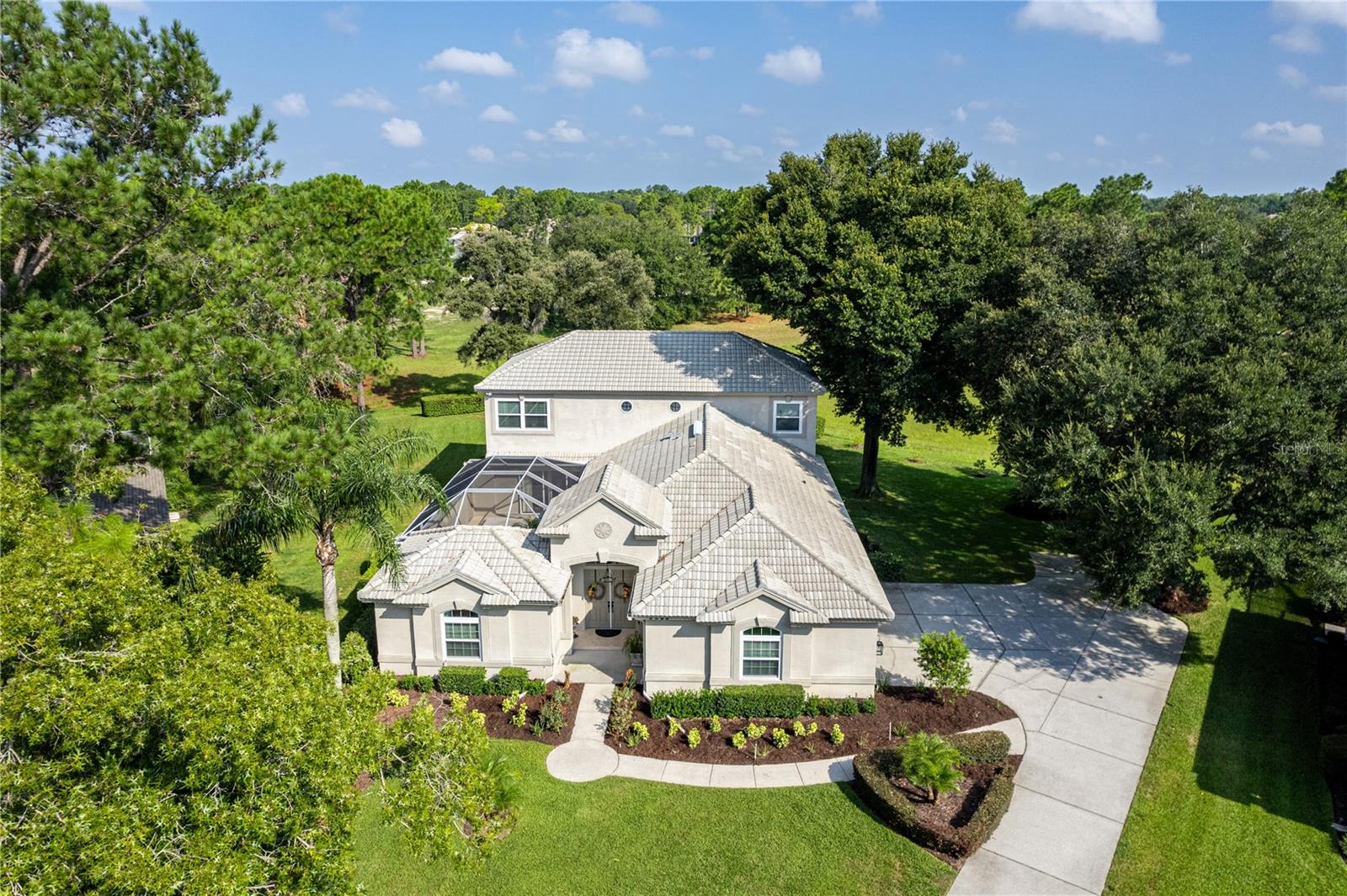 Paradise calls – will you be the one who answers? An exquisite experience from the tiled roof to the brand new dual pane windows, this spectacular 2-story home sits on the Silverthorn golf course. The secure gated neighborhood is a vivacious community with incredible amenities, including a clubhouse and The Legends restaurant, a community center, a jr-Olympic sized pool, fitness center, library, tennis courts, pickleball courts, and much more; plus, the HOA fees include cable and internet. Double front doors on this custom-built Rutenberg home reveal a dreamy courtyard featuring an in-ground pool with a fountain and an in-ground spa. Summer days call for lounging around the granite-topped tiki bar, sipping cool drinks from the mini fridge. Visitors can stay in the sizable cabana suite with beautiful laminate flooring, a walk-in closet, and a bathroom with a step-in shower. A functional floor plan in the main home offers flexibility for your living needs. The formal dining room has a built-in mirrored hutch and wet bar, so it could easily double as a formal sitting area or living room. The spacious family room is for game night, or cooler evenings curled up in front of the flickering glow of the gas fireplace, which is surrounded by a built-in entertainment center. You can slip out of another set of glass doors to the screened porch to take in the birdsong and the views of the backyard with your morning beverage. Overlooking the courtyard, you’ll also find a guest bedroom with dual closets on the main floor, along with a full bathroom. Cooking for 2 or 20? Doesn’t matter; the immaculate island kitchen is equipped with every modern convenience and elegant finish a cook could want, like granite counters, gray subway tile backsplash, a huge walk-in pantry, and gleaming stainless steel appliances. There’s even a built-in double oven and a sleek flat cooktop, along with designer light fixtures. Tucked back by the large eating nook is the staircase that leads to sanctuary: the primary suite and study. The massive primary suite dominates most of the upstairs space, containing dual walk-in closets, a large sitting area, another cozy gas fireplace, and a private balcony with a sweeping view of the course out back. Experience spa-like luxury in the primary bath with its dual sink vanities, large soaking tub, and glass walk-in shower. And just off the stairs, an impressive bonus room/study with built-in shelves and a desk awaits; it would make an excellent den, library, or even a home office. It also contains the entrance to a substantially-sized storage room, where you can safely stow your belongings in a temperature-controlled environment. The 2.5 car garage downstairs offers even more storage space in the form of a workbench and cabinets — now freshly painted along with the floor, walls, ceiling, and cabinets for a crisp, updated look. Both AC units have been recently replaced (2018 and 2022). Silverthorn is centrally located to plenty of shopping and dining options, and minutes from the Gulf of Mexico; access to Tampa via the Suncoast Parkway is quick and easy. Anderson Snow Park, with its amazing sports complex, and Veterans Memorial Park, with its popular walking trails, are both less than 6 miles away. Don’t forget to check out the world-famous mermaids at Weeki Wachee Springs State Park, which also has a canoe/kayak launch and a waterpark in the summer months. Make your dream life a reality, and schedule your tour to see this beauty today!