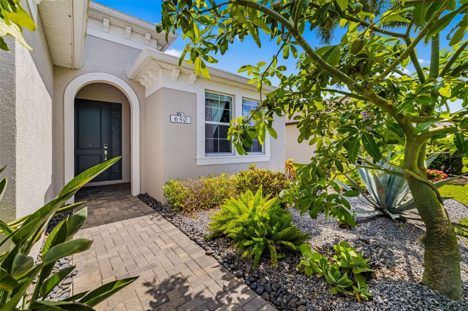 Multigenerational luxury Florida living in highly desirable Greyhawk Landing with Premium PRIVATE WATERVIEWS, 650 Rosemary Circle, Bradenton. Exudes modern luxury tastefully designed throughout beautifully appointed on an oversized corner lot, surrounded by lush tropical Florida palms. Built by Homes by Towne, this 4-bedroom, 2.5-bath residence offers timeless design and modern comfort on a spacious .27-acre corner lot with lush tropical landscaping that provides both privacy and curb appeal. Enjoy tranquil lake views from your fully screened, covered lanai and heated saltwater pool, with large covered areas, pre plumbed for an outdoor kitchen is ideal for relaxing or entertaining year-round.
Step inside to a bright and open floor plan featuring a great room with soaring tray ceilings, wood-look tile flooring, and thoughtfully selected finishes. The elegant dining room and cozy breakfast nook are enhanced with modern light fixtures. The kitchen is a chef’s dream, showcasing quartz countertops, a white tile backsplash, a center island, and stainless steel appliances including a gas range, microwave, refrigerator, and dishwasher.
The primary suite is a serene retreat with its own access to the lanai and pool, custom geometric accent wall, and designer lighting. A sliding barn door leads to the spa-like ensuite bath complete with dual sinks, a Roman walk-in shower, private water closet, makeup vanity, and a spacious walk-in closet. The additional bedrooms feature engineered hardwood flooring, and the home also includes a functional laundry room and a 3-car garage for added storage.
Greyhawk Landing offers unmatched resort-style amenities with a low HOA of just $70/year. Residents enjoy 24-hour gated security, two lagoon-style pools with spas, a fitness center, tennis and pickleball courts, basketball courts, multiple playgrounds, a fishing pier, baseball and soccer fields, and over five miles of scenic walking and biking trails. Ideally located near Lakewood Ranch, Sarasota, I-75, Tampa and Sarasota airports, and top-rated schools, this home is just minutes from world-renowned beaches like Siesta Key, Anna Maria Island, and Longboat Key, as well as championship golf, shopping at UTC Mall and St. Armands Circle, dining, boating, and more. This home offers not just luxury, but lifestyle, in a vibrant, nature-inspired community that truly has it all. Don’t miss your opportunity to experience Greyhawk Landing living at its finest in paradise. Schedule your private showing today!
