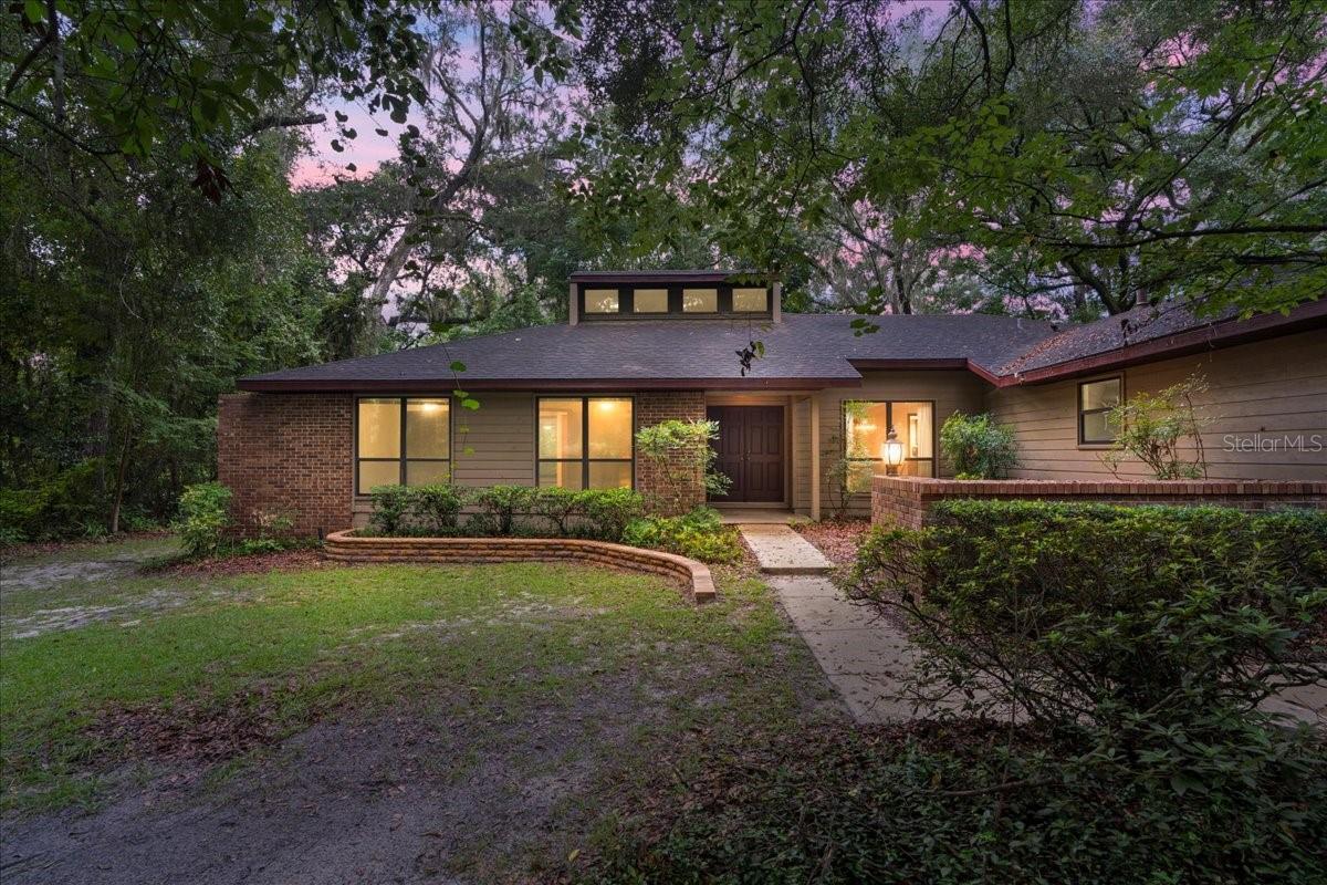 Priced to sell, this solidly built home has been lovingly cared for by its original owner and is ready for its next chapter. Step inside to a voluminous, light-filled great room featuring a brick fireplace, soaring transom windows, and floor-to-ceiling views of the private backyard. A formal dining room with large windows sits just off the entry, perfect for gatherings.
The thoughtfully designed split floor plan includes three bedrooms, two bathrooms, and generous storage throughout. The kitchen offers dual pantries, a breakfast bar, and an eat-in area overlooking the screened patio. The primary suite, tucked down the hall past the laundry room, features sliding doors to the deck with serene backyard views. Its en-suite bath includes a dual-sink vanity and a separate room with a large walk-in shower.
A spacious indoor laundry room with washer and dryer leads to the two-car garage. Recent updates include fresh exterior paint and a pumped and inspected septic system. Situated on an acre lot with no HOA, the property offers privacy, space to spread out, and endless potential.
Whether you’re seeking your next renovation project or a home you can personalize over time, this property presents excellent opportunity in a desirable SW Gainesville location.