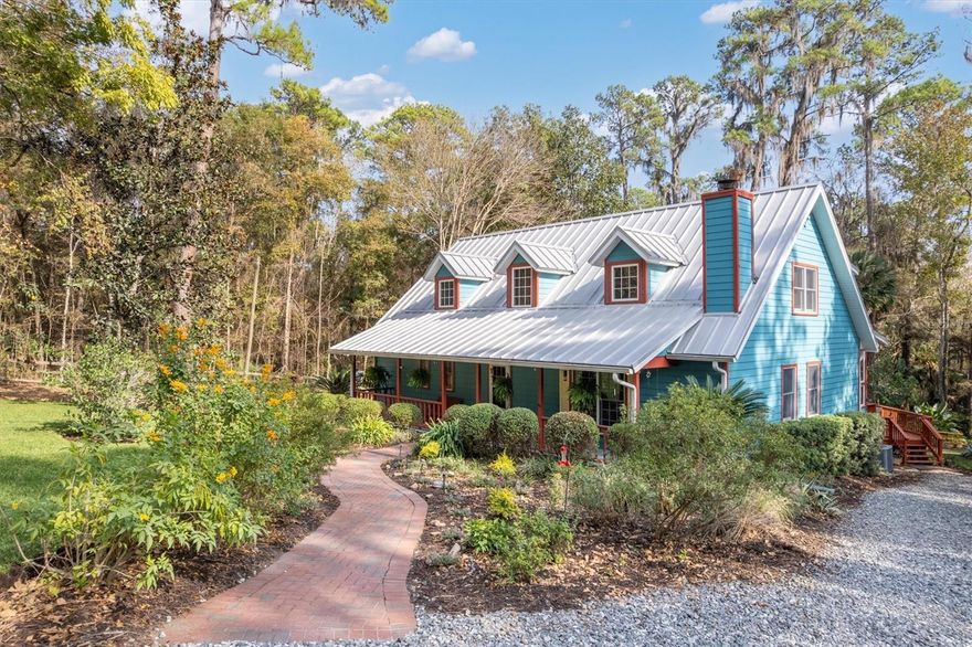 This home and property is SPECIAL!  Tucked away near the historic charm of Micanopy and just 15 minutes from Gainesville, UF Health, the VA, and the University of Florida, this exceptional estate set on over 6 acres offers the perfect blend of resort-style living, connection to nature, and everyday convenience. Inside the home, discover rich architectural details and a thoughtfully updated layout designed to seamlessly bring the outdoors inside. Floor-to-ceiling windows fill the home with natural light, while a striking stone fireplace anchors the living room with warmth and character. The shared living spaces feature elegant tile and reclaimed heart-of-pine flooring opening effortlessly to a screened lanai—ideal for morning coffee or unwinding at the end of the day.  Designed with entertaining in mind, the kitchen boasts beautiful stone countertops, abundant cabinetry, a generous pantry, a dine-in area, and a breakfast bar that connects to the Great Room. Additional highlights include a formal dining room, separate living room, and the convenience of a first-floor laundry room! The primary suite serves as a private retreat, complete with a soaking tub, oversized walk-in shower, and dual vanities. Upstairs, there are three additional bedrooms PLUS a versatile office or fifth bedroom with its own private deck, all centered around a spacious “bonus” living area.  Step outside to your own private oasis, where a tranquil water feature and cabana create the perfect setting for both entertaining and quiet relaxation surrounded by the natural beauty of “Old Florida.” The property is dotted with fruit trees and a variety of native Florida foliage, while the gentle rolling landscape offers a unique, almost mountain-like feel reminiscent of North Carolina.  Golf enthusiasts will love the private tee box and driving range—your very own “19th hole.” With no HOA, a durable metal roof, freshly painted exterior, and the added benefit of lower Marion County taxes, this home is a wonderful Value!  The property is only a also provides convenient access (approximately 30 minutes) to Ocala!  A rare combination of privacy, luxury, and location—this one-of-a-kind property truly has it all!