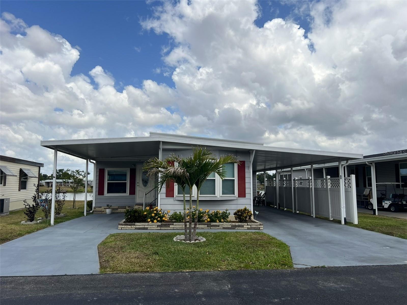 PRICE REDUCED! This UPDATED & MOVE-IN READY 2 Bedroom, 2 Bathroom manufactured home in the 55+ Floral Lakes Community in Bartow, FL is situated waterfront on Lake Flora. Interior walls and ceilings have been finished in drywall; double pane windows with shades have been installed throughout; whole home has been replumbed; new metal roof and new water heater in 2022; new A/C in 2019; PLUS dock with composite decking and electrical. This home features a spacious Kitchen with breakfast bar, stainless finish appliances, breakfast bar and a closet pantry; a separate Dining Area; Living Room with beautiful lake views; a second living area in the front of the home; Primary Bedroom with en-suite bathroom; spacious 2nd Bedroom with bay windows; screen enclosed rear porch; workshop storage; inside laundry room (washer and dryer included); 3 carport spaces for vehicles and golf carts with privacy panel and beautiful new landscaping to include Christmas Palms and Crape Mytles.
The Primary Bedroom with dual closets (mirrored door) and en-suite bathroom features a custom tiled shower enclosure, single vanity, and linen closet. The Guest Bathroom features a single vanity and custom tiled shower.
Located in central Florida, between Tampa and Orlando, this golf cart friendly community is near the Bartow Civic Center, Bartow Public Library, and Mary Holland Park. Here you OWN YOUR LAND (no lot rent) and pay low monthly HOA fees. The Floral Lakes community offers access to a stocked pond with community boat ramp and dock. Clubhouse amenities include recreation space, shuffleboard, putting green, and large heated swimming pool. Social clubs, dances, exercise, pot lucks, and MORE! Association approval is required for purchase. Call your Realtor today for more information and to schedule a showing!