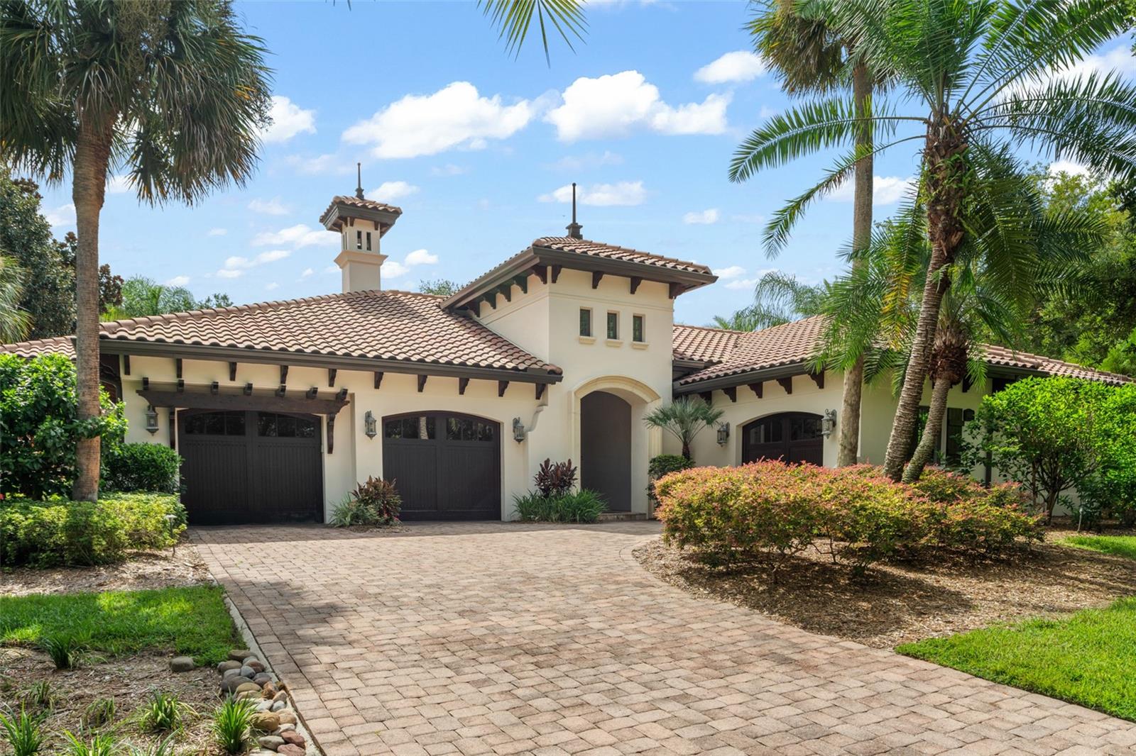 Discover the effortless blend of luxury, privacy, and modern design in this lovely Gardens of Isleworth villa.  Featuring timeless elegance, this beautiful three-bedroom, four-bathroom custom villa, where every detail has been thoughtfully curated to create a refined sanctuary for everyday living and entertaining. Beyond the stately arched main entry door lies a secluded courtyard oasis—a private retreat centered around a sparkling pool, serene waterfall feature, and generous lounging areas. Whether basking in the sun or relaxing beneath the stars, this outdoor haven sets the tone for the extraordinary spaces within. Designed to embrace indoor-outdoor living, the oversized courtyard welcomes you with a seamless open-plan layout connecting the pool, summer kitchen, and a charming guest cabana. Perfect for hosting or escaping, the cabana offers a private retreat for guests or a peaceful haven for the homeowner. Inside the main residence, a sense of contemporary sophistication flows through the light-filled kitchen, elegant dining room—highlighted by a statement chandelier—and the spacious grand room. French doors throughout invite the outdoors in, offering lush views from nearly every space and extending the living area to multiple porches and verandas. The living room, centered around a calming fireplace, is the perfect spot to unwind after a long day, while the spa and cascading waterfall nearby add to the sensory appeal. Retreat to the expansive master suite, where a private porch overlooks vibrant greenery, offering a peaceful start and end to each day. Additional property highlights include a cozy morning room, a dedicated office with custom Burl wood built-ins, and a series of intimate outdoor and indoor spaces designed to inspire comfort and connection.