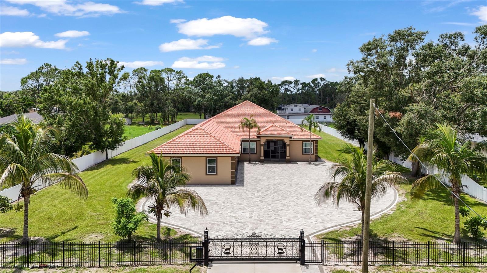 Looking for a NEW custom built home on over a 1 acre lot and 3100sf + with a neighborhood feel but NO HOA, NO CDD, Flood Zone X, Home Office, 3 Car Garage and plenty of room for the TOYS - well we have just the home! Welcome to this exceptionally built modern ranch-style home with private gate, nestled on a level 1-acre lot in the heart of Bradenton. Built in 2021, this home was built to the newest building codes with a high-quality tile roof, masonry construction and stucco exterior for durability and low maintenance. This expansive floor plan boasts 3,167?sf offering true one-level living with 4 bedrooms, 3.5 baths, a private den or office with separate entryway ideal for families, remote work or multigenerational living!! You will fall in love with the sprawling covered outdoor space adding so much more square footage to your home with bathroom access and ready for your custom outdoor kitchen, this space truly makes indoor outdoor living a dream! This home combines modern comfort with custom finishes, providing a rare opportunity for luxury one-level living including custom woodwork, stunning porcelain tiles throughout, tray ceilings, recessed lighting throughout and so much more! The gourmet kitchen features designer cabinetry, quartz countertops, stunning quartz waterfall island, stainless steel appliances and a large walk-in pantry! The primary suite boasts his and her closets and a gorgeous en-suite! The home offers three additional bedrooms and well-appointed bathrooms for comfort and flexibility. This home has an amazing level 1 Acre Lot and a fenced backyard, a custom paver patio with built in firepit and seating for the whole family to enjoy! Want a pool, there is plenty of space to add yours! Stunning curb appeal is complimented by the remote controlled private gate and wide, paver-lined driveway with ample room for parking! Finally, the home features an attached oversized garage with 3 parking spaces and tons of room for storage! Whether you're hosting indoors or out, working from the den, or enjoying neighborhood conveniences, this property has been designed for both relaxation and everyday function. Conveniently located to premiere restaurants, shopping, stunning beaches, Lakewood Ranch's Main St or I75 Access!