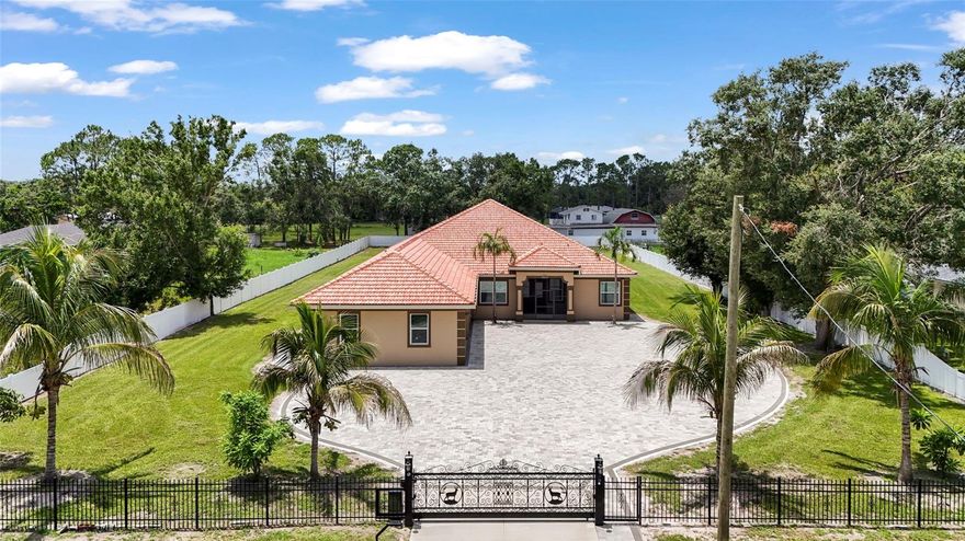 Looking for a NEW custom built home on over a 1 acre lot and 3100sf + with a neighborhood feel but NO HOA, NO CDD, Flood Zone X, Home Office, 3 Car Garage and plenty of room for the TOYS - well we have just the home! Welcome to this exceptionally built modern ranch-style home with private gate, nestled on a level 1-acre lot in the heart of Bradenton. Built in 2021, this home was built to the newest building codes with a high-quality tile roof, masonry construction and stucco exterior for durability and low maintenance. This expansive floor plan boasts 3,167?sf offering true one-level living with 4 bedrooms, 3.5 baths, a private den or office with separate entryway ideal for families, remote work or multigenerational living!! You will fall in love with the sprawling covered outdoor space adding so much more square footage to your home with bathroom access and ready for your custom outdoor kitchen, this space truly makes indoor outdoor living a dream! This home combines modern comfort with custom finishes, providing a rare opportunity for luxury one-level living including custom woodwork, stunning porcelain tiles throughout, tray ceilings, recessed lighting throughout and so much more!  The gourmet kitchen features designer cabinetry, quartz countertops, stunning quartz waterfall island, stainless steel appliances and a large walk-in pantry! The primary suite boasts his and her closets and a gorgeous en-suite! The home offers three additional bedrooms and well-appointed bathrooms for comfort and flexibility. This home has an amazing level 1 Acre Lot and a fenced backyard, a custom paver patio with built in firepit and seating for the whole family to enjoy! Want a pool, there is plenty of space to add yours! Stunning curb appeal is complimented by the remote controlled private gate and wide, paver-lined driveway with ample room for parking! Finally, the home features an attached oversized garage with 3 parking spaces and tons of room for storage! Whether you're hosting indoors or out, working from the den, or enjoying neighborhood conveniences, this property has been designed for both relaxation and everyday function. Conveniently located to premiere restaurants, shopping, stunning beaches, Lakewood Ranch's Main St or I75 Access!