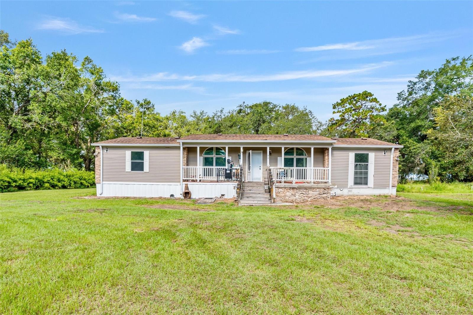 **Your Private 5-Acre Florida Retreat Awaits!** This is a rare opportunity to own 5 acres of peaceful countryside in the heart of Lady Lake. Surrounded by the gentle sway of mature trees and the open beauty of Florida’s rural landscape, this 3-bedroom, 2-bathroom manufactured home, built in 1999, offers both comfort and endless potential. Wake up to golden sunrises over your sprawling property and enjoy quiet mornings with nothing but the sounds of nature. Whether you dream of starting a small farm, keeping horses, planting lush gardens, or simply enjoying the space to roam, this land is ready to bring your vision to life. A powered workshop with electricity is already on-site—perfect for hobbies, storage, or transforming into your dream creative space. Inside, the home provides a warm and functional layout with a cozy living area, a spacious kitchen for gathering, and a primary suite designed for relaxation. Large windows invite in natural light, framing views of the surrounding greenery and making every room feel connected to the outdoors. With ample room for future expansions, additional outbuildings, barns, or even a pool, the possibilities are truly limitless. Located just minutes from shopping, dining, and The Villages, you’ll enjoy the perfect balance of seclusion and convenience. Come experience the freedom, privacy, and beauty this property has to offer—schedule your private showing today and start living the country lifestyle you’ve been dreaming of!
