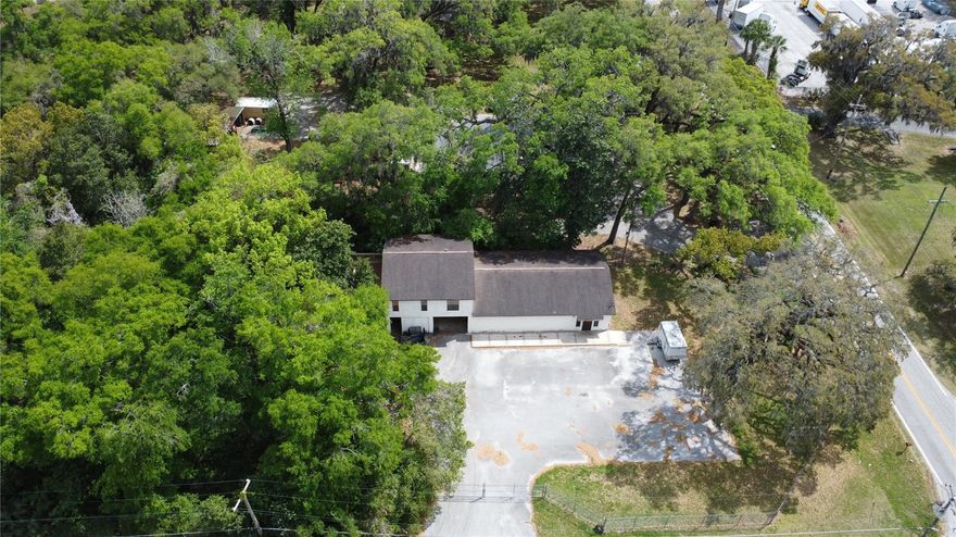 Turnkey property featuring a 1,536 SF masonry-constructed building with a second-story 928 SF 2-bedroom/1-bathroom apartment, situated on 0.75 acres in North Ocala's industrial corridor. Originally constructed in 1988, the building includes a large open shop floor, workshop/service area with workbenches and utility sink, front retail/reception area with service counter, and a covered drive-in garage bay. The apartment above offers a full kitchen, walk-in shower, and hardwood-style flooring, providing an owner-operator housing option or supplemental rental income. The fenced perimeter provides security for equipment and vehicles, while the paved parking area and open yard space offer strong potential for a laydown yard, a practical advantage for contractors, distributors, or service-based businesses in the surrounding industrial market. There is also an established channel that directs stormwater towards the DRA at the back of the property.