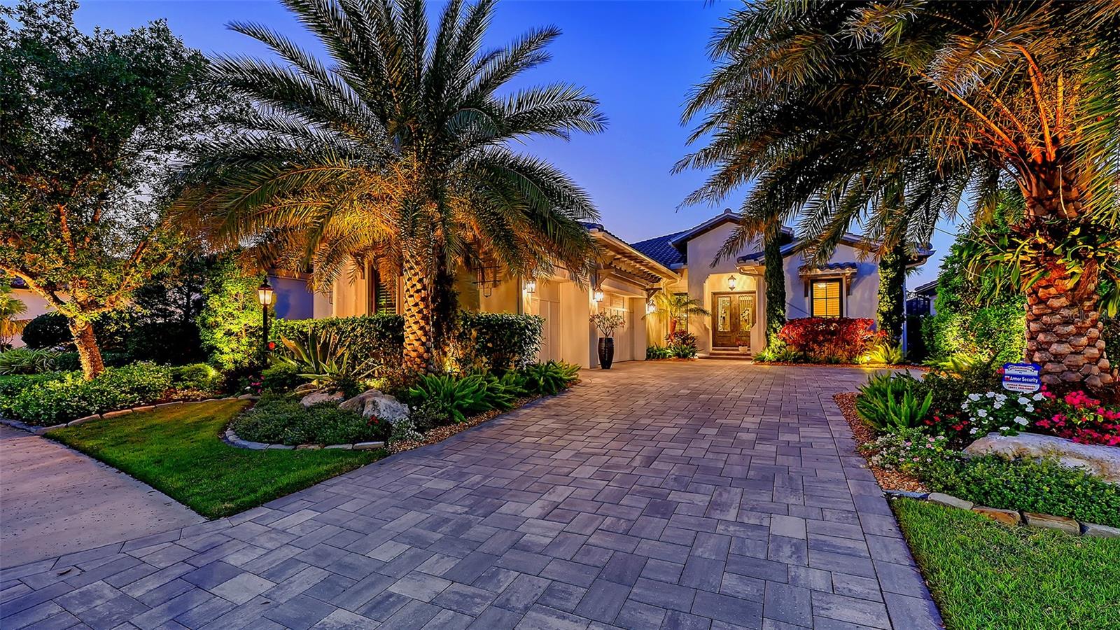 Located in the highly sought-after Matera section of The Lake Club, this green-certified Wetherington home, built in 2021, offers luxurious upgrades and custom details throughout. Enter through double handcrafted iron doors into an open, airy floor plan with designer chandeliers, plantation shutters, unique square LED recessed lighting, tall crown molding and porcelain tile floors throughout. The great room features a cypress wood beam coffered ceiling and a shiplap feature wall. Double doors off the great room open into the home office/den.
Four panels of sliding glass doors pocket so a whole wall of the great room opens up to the expansive travertine lanai with a heated saltwater pool and spa. Enjoy alfresco dining by the outdoor kitchen, its stainless steel grill and beverage cooler. The chef’s kitchen includes GE Monogram appliances, quartz countertops, white cabinetry, mosaic glass tile backsplashes, a hidden pantry room, and a large central island/breakfast bar. The adjacent dining room overlooks the lanai and lush landscaping. The primary suite is a private retreat with a double-tray ceiling and large windows. The spa-like primary bath includes a walk-in shower, freestanding tub, quartz counters, and shiplap accents. The two guest bedrooms with ensuite baths and custom closets are both positioned to provide comfort and privacy. The large laundry room offers ample counter space, and the Wetherington signature "Florida Basement" offers extra storage. The 3-car side-loading garage features epoxy flooring. In the Matera section of The Lake Club, the HOA maintains the grounds, irrigation, and your pool, so you can enjoy carefree living. The Lake Club offers resort-style amenities, including a grand clubhouse, restaurant, pool, tennis, fitness center, walking trails, and interlinking lakes for kayaking and fishing.