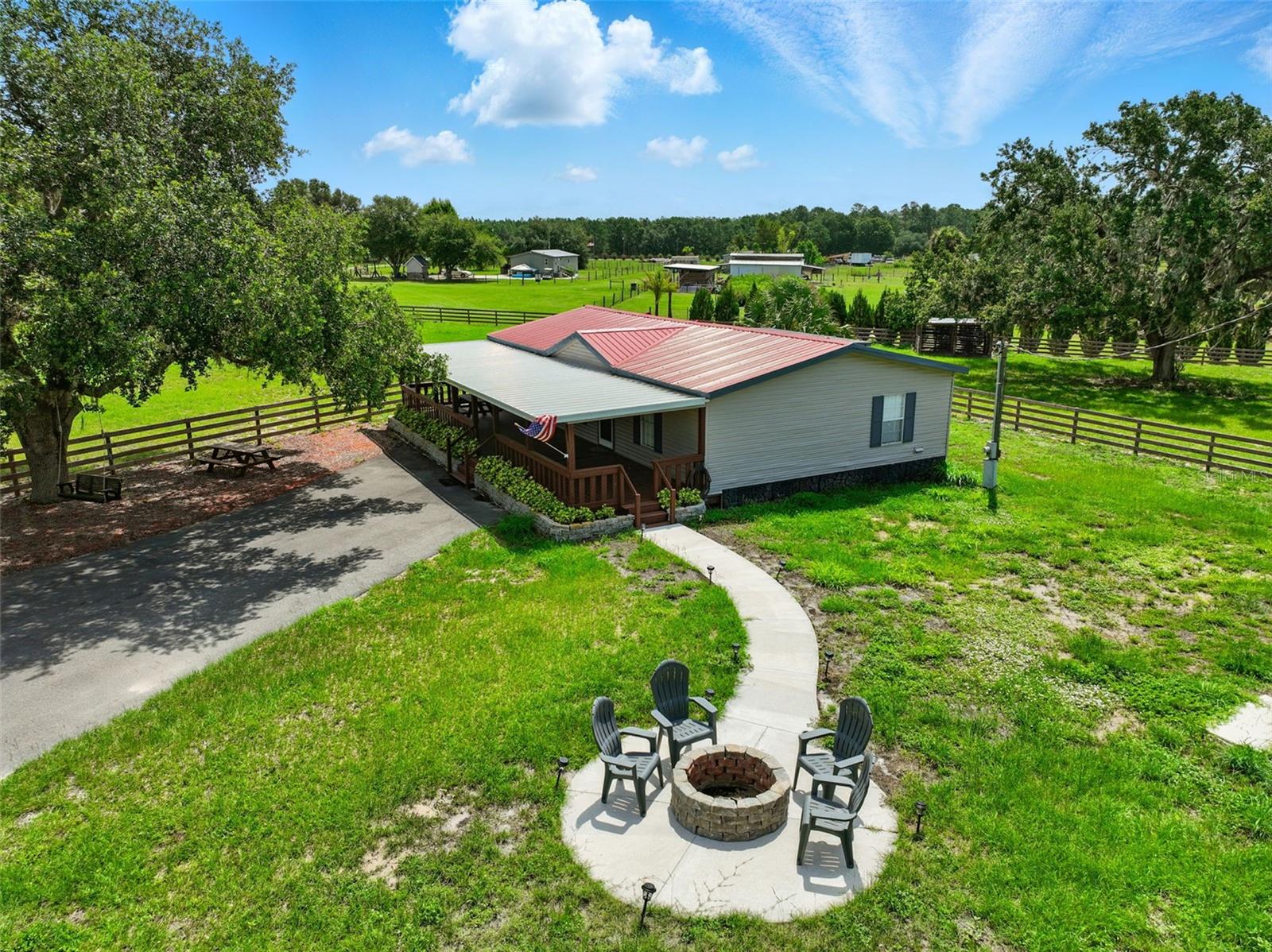 One or more photo(s) has been virtually staged. Welcome to your private equestrian retreat! This beautifully remodeled 3-bedroom, 2-bath home sits on nearly 5 fenced acres and features a fully updated interior with luxury finishes throughout—granite countertops, luxury vinyl plank flooring, all-natural pine doors, brand-new appliances, Moen fixtures, and walk-in closets in every bedroom. Enjoy an open, split floorplan, a charming front porch, and a large screened-in back porch (easily convertible to a Florida room for additional living space).
Equestrians and entrepreneurs alike will love the 12-stall horse barn, complete with water in every stall, an integrated fly spray system, 12-ft concrete center aisle (wide enough for vehicles), a wash station, storage room, and brand new roof on the home. The land is cross-fenced into 4 pastures (2 with animal shelters, 1 marshy in rainy season), with mature oaks providing ample shade and custom lock-clip fencing—no chains needed!
A paved and patterned driveway stretches from the gated entrance (with electric opener and keypad) all the way to the barn for seamless access. Other upgrades include a resurfaced and painted roof on the barn, serviced AC, septic, well, and water heater. Enjoy peaceful evenings by the custom firepit or swinging under the oak tree—this one-of-a-kind property offers luxury, function, and endless opportunity.