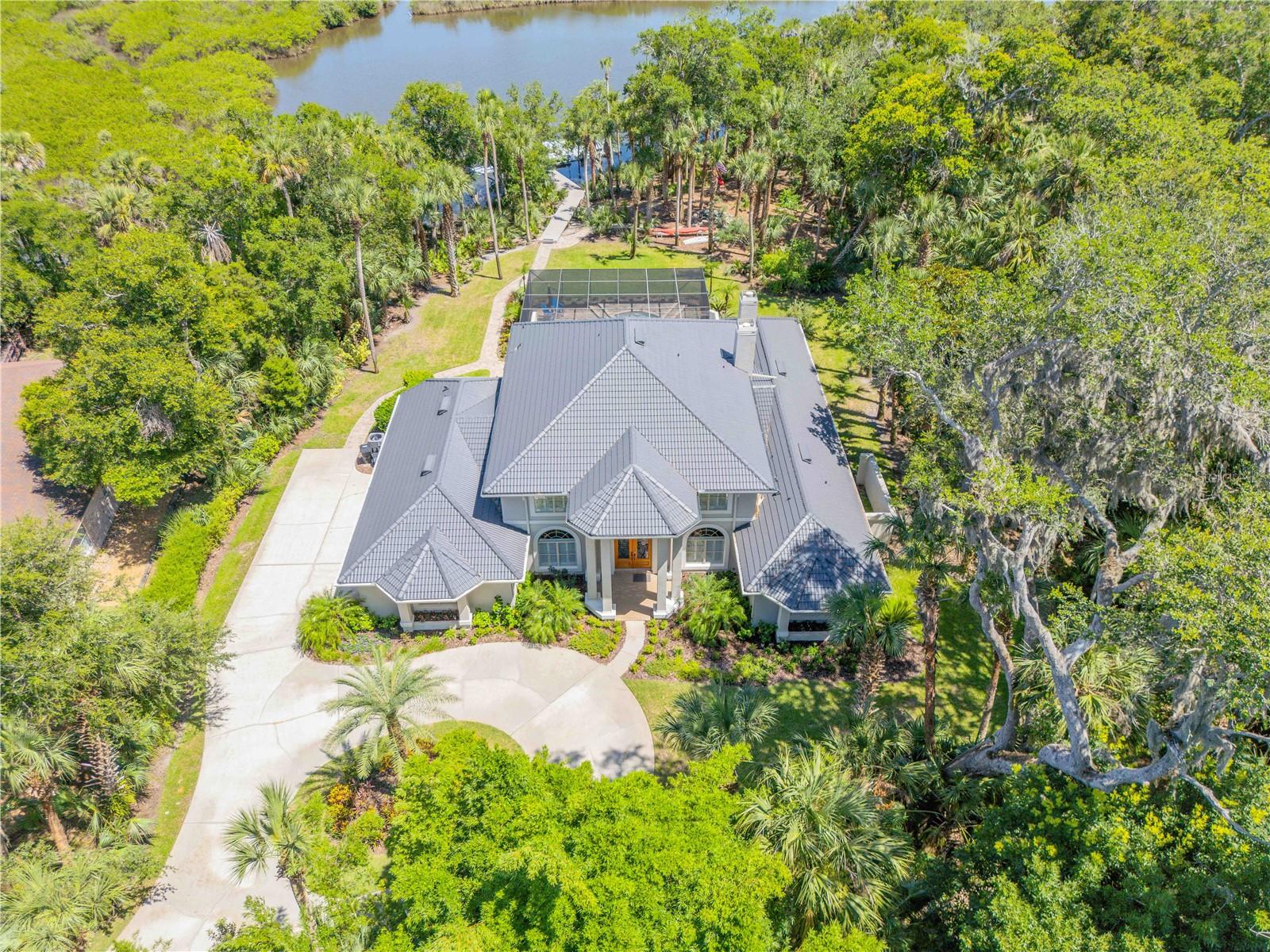 Stunning 5 Bdr, 4 1/2 Ba, waterfront pool estate home at 6325 Palmas Bay, located in the gated Palmas Bay Club within the Riverwood community of Port Orange. Positioned on a semi private cul de sac along Spruce Creek with direct access to the Halifax River and Intracoastal Waterway, ideal for boating enthusiasts. This home features a circular driveway, lush landscaping, and a 3 car garage. Inside the home is a grand foyer, formal dining, spacious kitchen with island and breakfast nook, and a large living room with gas fireplace. Sliders open to a screened outdoor living area, summer kitchen, and fully screened in pool. The first floor includes the primary suite, pool bath, laundry, and media room. Upstairs offers three bedrooms, two full baths, and a divided sitting area. A paver walkway leads to a large deck and floating dock, perfect for fishing, relaxing, or launching your boat. Located minutes to beaches, dining, shopping, and top rated schools in Port Orange. POF/Pre-approval for showings.