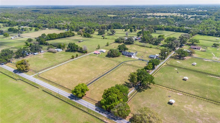 Set on 12-acres in Central Florida’s renowned horse country, this fully equipped horse farm offers a comprehensive blend of functionality, comfort, and thoughtful design. Fenced and gated, the property features two entrances– one leading towards the residences and the other to the barn and workshop. The main residence is a spacious, custom 4-bedroom, 3-bath home that features a covered front porch, attractive brick exterior accents, and over 3,000 sqft of space. The interiors are defined by abundant natural light, tall ceilings, and ceramic tile flooring throughout, making the space warm and inviting. Placed between the formal dining room and the main living area, the kitchen is thoughtfully appointed with stainless steel appliances, extensive cabinet storage and counter space, a center island with breakfast bar and wine storage, and an additional pantry. All bedrooms are well-sized and versatile, but the primary suite provides a true retreat with a large layout, walk-in closet, and a private en-suite bath with soaking tub, glass-door shower, and dual sinks. Step outside to enjoy a screened-in, in-ground pool with expansive deck space, along with covered and screened porches that overlook the surrounding pastures. With its own gate and fenced-in yards, a secondary home is also established on the property, offering a total of 3-bedrooms and 2-baths and luxury vinyl flooring throughout– an ideal option for long-term guests, seasonal rental space, or for a farm manager. For equestrians, the 6 stall center aisle equipped with fly spray system, automatic waterers, and wash rack provides plenty of room for horses, with an additional storage shed located just outside for additional tack or feed storage. A total of 4-paddocks with automatic waterers are currently in-place, providing ample opportunity to train year-round, further divide into smaller paddocks, or even establish an arena or round pen as desired. A large 3 bay workshop with bathroom is also in place, complete with an additional studio apartment with a kitchenette and washer/dryer, as well as a separate remodeled 1 bedroom RV with outdoor deck, both of which are currently listed on AIRBNB as income producing properties. Located just a few minutes from Sweet Dixie South and Majestic Oaks and a short drive from both the World Equestrian Center (WEC) and HITS, this farm is ideal for a variety of disciplines looking to get the most out of Horse Country!