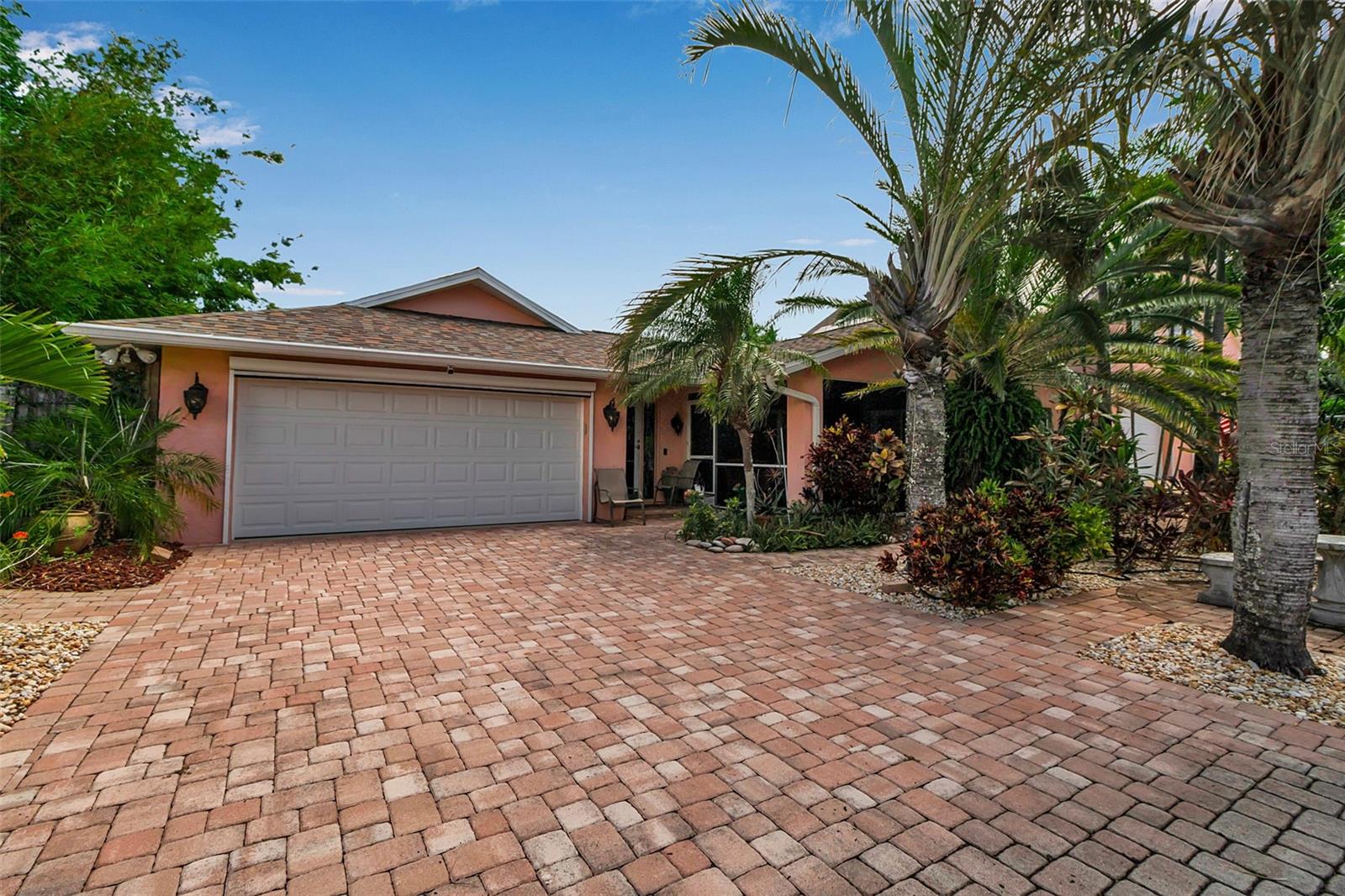 Just 800 feet from Palma Sola Bay and minutes from the white sands of Anna Maria Island, this custom 4-bedroom, 5-bathroom home offers exceptional flexibility, privacy, and indoor-outdoor living. Located on a quiet dead-end street, this property is ideal for multi-generational living, hosting guests, or simply enjoying your own private retreat near the coast.
Inside, the split open-concept layout features two spacious primary suites, each with walk-in closets, tile flooring throughout, recessed can lighting, and a thoughtfully designed flow perfect for everyday living or entertaining. The paid-in-full solar system helps keep electric bills impressively low year-round.
Outdoor spaces are equally impressive: relax in the screened front lanai or entertain under the covered back patio, overlooking the heated pool and spa. Both the attached and detached garages include electronic screen doors, allowing breezes while keeping bugs out.
The detached 30x40 garage is a true standout—featuring 2+ car capacity, a concrete-encased 14’ x 9’ secure vault ideal for valuables or collectibles, a full bath downstairs, and a guest-ready upstairs with two bedrooms, another full bath, skylights, and a central living area. There’s also plumbing and electrical in place to easily finish a kitchenette, making this space perfect for guests, adult children, or a potential mother-in-law suite.
The exterior is as beautiful as it is unique, with paver driveways, winding garden pathways, and mature landscaping that includes a bamboo garden and cactus garden for a truly Florida-inspired setting.
Located just a short bike ride to Potosueno Park and the Palma Sola Boat Basin, this one-of-a-kind home offers space, style, and location—just 4 miles from the beach.