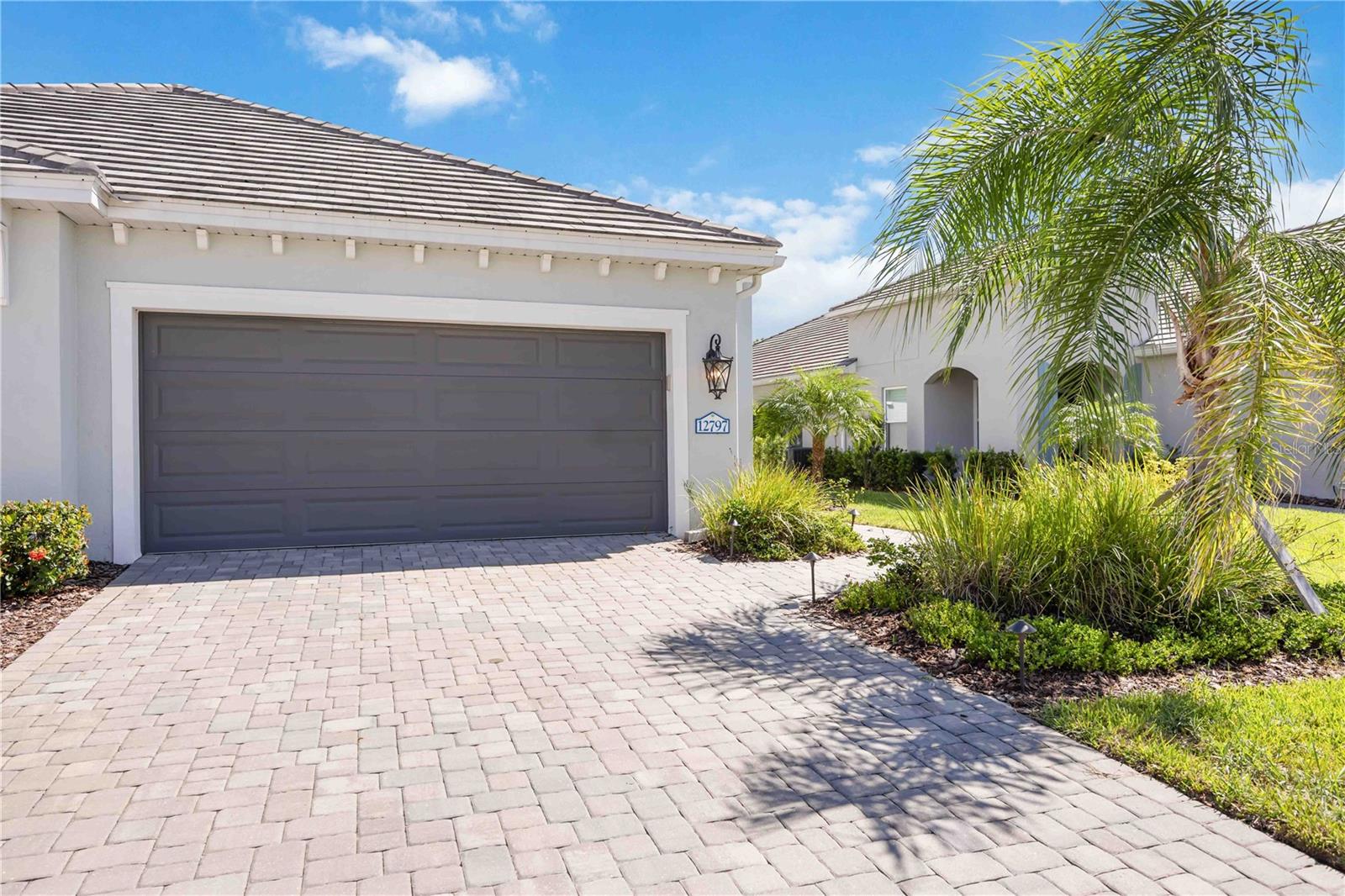 Step into resort-style living with this stunning 2022 villa in the sought-after Grand Palm community—where every detail has been thoughtfully designed for comfort, beauty, and convenience. This 2-bedroom, 2-bathroom home with a den offers 1,632 square feet of elegant living space, all wrapped in a bright, open floor plan perfect for both relaxing and entertaining. High-end finishes shine throughout, from 8-foot doors and custom California Closets to designer light fixtures and plantation shutters. The owner has spared no expense in creating a space that feels brand-new, yet warm and inviting. The great room, with its coffered ceiling, flows effortlessly into the chef’s kitchen, where you’ll find premium appliances—including a gas range—ample counter space, and rich tile flooring underfoot. The den features gorgeous hardwood floors, adding a cozy touch. Your private owner’s suite feels like a personal retreat, with a spa-inspired bathroom and not one, but two California Closets. The second bedroom also offers a custom closet, ensuring every inch of space is beautifully organized. Step outside to enjoy Florida living at its best: a covered, extended screened lanai with an outdoor kitchen, gas grill, and electronic privacy blinds. The front of the home is framed with lush landscaping and accent lighting, while the two-car garage features a durable epoxy floor. Added peace of mind comes with hurricane-impact windows and doors, a smart home system, and a full security setup with cameras. Grand Palm’s unmatched amenities make every day feel like vacation—swimming pools, tennis, pickleball, volleyball, basketball, a fitness center, 28 miles of trails, parks, dog parks, playgrounds, and a vibrant clubhouse. All this, just minutes from downtown Venice and its award-winning beaches. This villa is more than move-in ready—it’s move-in perfect. Schedule your private showing today and start living the lifestyle you deserve.