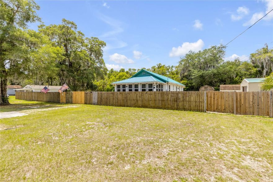 Country Living in the City! Just 2 miles from the charming Historic Downtown District of DeLand and Stetson University, this unique property offers space, flexibility, and endless possibilities. Bring your RVs, boats, work vehicles, or equipment — this oversized 100x155 fully fenced lot features a 12-foot front gate and three large outbuildings with electricity, two of which include loft storage.
The solidly built historic bungalow, originally constructed in 1939, has been thoughtfully updated while maintaining its original charm. Major improvements include updated plumbing and electrical systems, a metal roof (2017), new HVAC (2023), 19 double-pane windows (2016), upgraded electrical panel (2018), blown-in attic insulation, and a tankless water heater. The remodeled kitchen features granite countertops and ceramic tile flooring. Additional plumbing upgrades include new drains, toilet, and shower.

Enjoy relaxing in the bright Florida Room with French doors and antique hardware, while sunshades help keep the home energy efficient year-round. Zoning allows for an ADU or RV setup with separate electric and water hookups, making this property ideal for multi-generational living, a home business, hobby storage, or future income potential.
