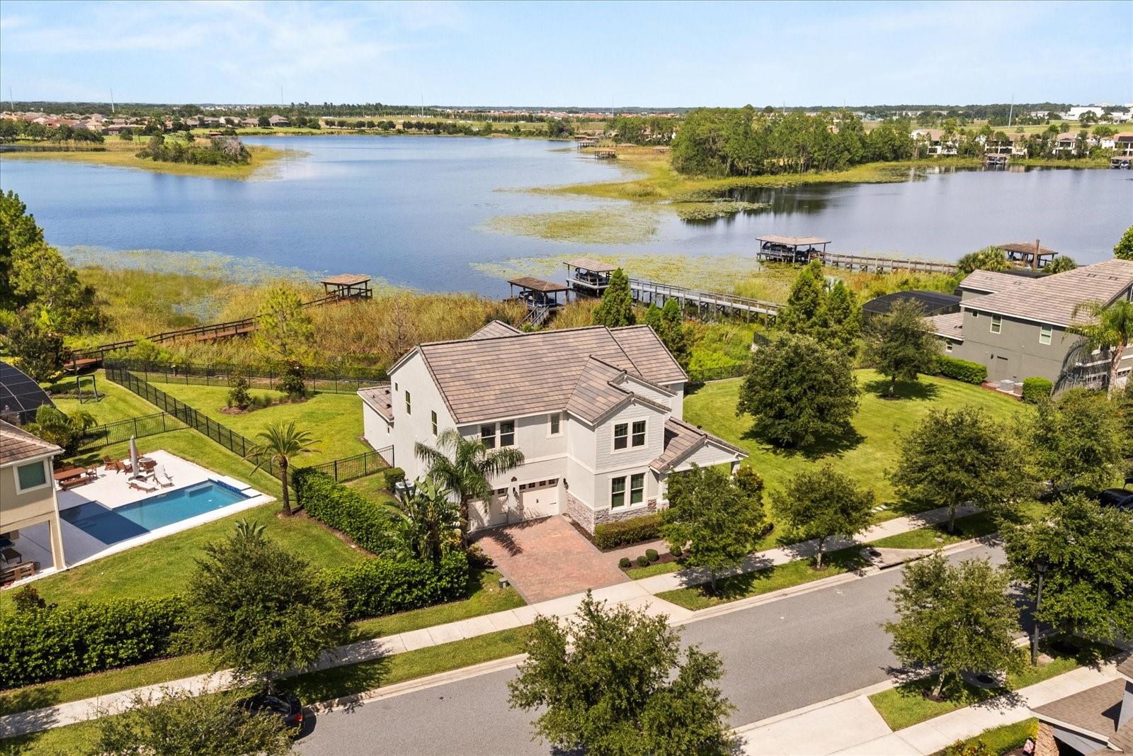 OFFERED with a 2021 LOWE PONTOON BOAT! Lakefront Luxury in Waterleigh with Private Dock and Fireworks Views. Welcome to the perfect blend of comfort, function, and lakeside living in the highly sought-after Waterleigh community. This spacious home sits on a fully fenced 1/3-acre lot with over 100' fronting the lake in the back and 90'+ of open green space to the side; featuring a private dock with low-maintenance composite boards, a pontoon boat lift, and a peaceful sitting area—offering a front-row seat to nightly Disney fireworks from your dock or living room. Inside, no detail has been overlooked. The home boasts durable wood-look tile downstairs and luxury vinyl plank flooring upstairs—no carpet in sight. The open-concept layout seamlessly connects the kitchen, dining, and family rooms, all with stunning lake views. The kitchen is a chef’s dream, complete with 42” cabinets, a 4-seat island, 5-burner stove, double convection oven, butler’s pantry, walk-in pantry, and built-in wine rack. The extra-large primary suite is located on the first floor and showcases crown molding, tray ceiling, huge walk-in closet and serene lake views. The primary bathroom is a dream with quartz counters, dual vanities, a makeup counter, and a walk-in double shower. Upstairs, a versatile loft offers the ideal space for a game room, media room, or second living area. All bedrooms are generously sized with walk-in closets, and there’s no shortage of storage with additional closets throughout. Work from home in the dedicated office, enjoy surround sound in the family room (pre-wired for 5.1), and take advantage of the spacious laundry room with built-in cabinetry and counter space. The 3-car garage features epoxy flooring, and the home is pre-wired for a pool if you wish to expand your outdoor living. Waterleigh offers unmatched amenities including resort-style pools, playgrounds, sports fields, fitness centers, and even a Publix right at the entrance. Lawn, landscape and irrigation maintenance are included with the HOA dues, and you're just minutes from the 429, Disney, shopping, dining, and top-rated schools. This is Florida living at its best.