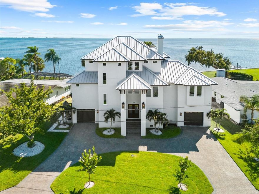 A rare offering where modern elegance meets coastal serenity—welcome to 110 Carlyle Drive, a breathtaking Gulf-front estate nestled on the exclusive shores of Indian Bluff Island. Custom-built in 2022 and meticulously designed for elevated living, this residence commands 80 feet of pristine waterfront along the Intracoastal, with direct access to the Gulf of Mexico.

Beyond the private circular drive, a statement double-door entry sets the tone for the refined interiors that follow. Soaring ceilings, expansive walls of glass, and hand-selected finishes create a luminous, open atmosphere that celebrates the water views from nearly every room. At the heart of the home, a grand great room with a gas fireplace seamlessly flows into the designer chef’s kitchen—complete with solid wood cabinetry, a suite of luxury appliances, and panoramic views that make everyday living feel extraordinary.

The primary suite is a sanctuary of sophistication, framed by water vistas and complete with an indulgent spa bath, dual vanities, and a custom walk-in closet. Upstairs, three additional bedrooms feature en-suite baths and walk-in closets, each designed with space, privacy, and style in mind.

Step outside into your own waterfront resort. A saltwater pool glistens beneath the sun, surrounded by tropical landscaping and expansive outdoor living space, perfect for year-round entertaining. A private dock with a 10,000 lb lift, composite decking, water/electric hookup, and a concrete seawall elevates the boating lifestyle.

Crafted with block construction, a tile roof, impact-rated windows, and timeless architectural elements, this home is equal parts beauty and resilience. Additional features include an oversized four-car garage, golf cart parking, elevator access, and interior laundry.

Located in a quiet, established enclave just minutes from top-rated beaches, golf and country clubs, and downtown Palm Harbor. Zoned for the highly sought-after Palm Harbor University High School.

This is more than a home—it’s a coastal legacy built to last, where every sunrise and sunset is yours to own.