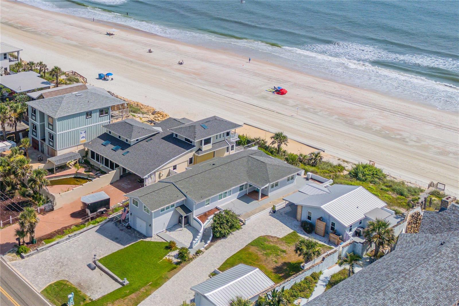This charming, timeless beachfront home has been fully renovated from top to bottom. This meticulously upgraded residence offers direct access to the pristine, no-drive beach, delivering an unparalleled lifestyle of coastal beauty and modern comfort. Every detail has been thoughtfully reimagined, including a new roof, hurricane-impact windows, updated electrical and plumbing, enhanced seawall, new siding, stairs, water heater, interior/exterior doors, and stylish fixtures throughout. Inside, enjoy elegant plantation shutters, luxurious vinyl plank flooring, chic baseboards and a gleaming open kitchen with quartz countertops. The thoughtfully designed owner’s suite offers immediate access to a beautifully renovated bath for privacy and guest functionality. Breathtaking ocean views fill the living and dining areas, leading to an expansive patio ideal for entertaining or unwinding to the sound of waves. The lower level has been transformed into a versatile entertainment space, thoughtfully converted to maximize living area near the sand, with plumbing access available for a future bath addition. An oversized paver driveway provides ample parking for vehicles and recreational equipment. Fully furnished and move-in ready, this beachfront gem delivers exceptional value in one of Florida's sought-after no-drive beach communities.