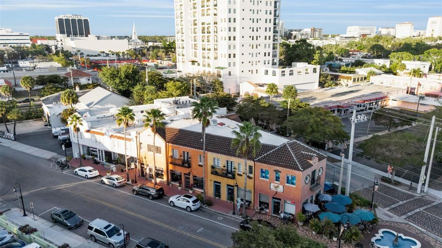 The Historic Pineapple Apartments, the centerpiece of Burns Square. This building has deep ties to Sarasota history, built by Owen Burns (our city's first developer) in 1925. Last purchased in 1986, you will never walk a more curated and cared-for building. It's a step back into the Roaring '20s and a modern-day reminder that community is local. At one time an apartment building, it now serves as a thriving vacation rental. It has 8 suites (could be 13), 7 retail shops below, and a 3,000 sq ft owner's suite. Wrought-iron balconies align the exterior walls, Venetian plaster the interiors, multiple exposed beams, and a historical monument next to the fountain at Little Five Points. It's Sarasota's "Flatiron Building," triangulated architecture, impossible to go unnoticed. It is the entrance to downtown from the south, a beacon, a landmark for our great city.