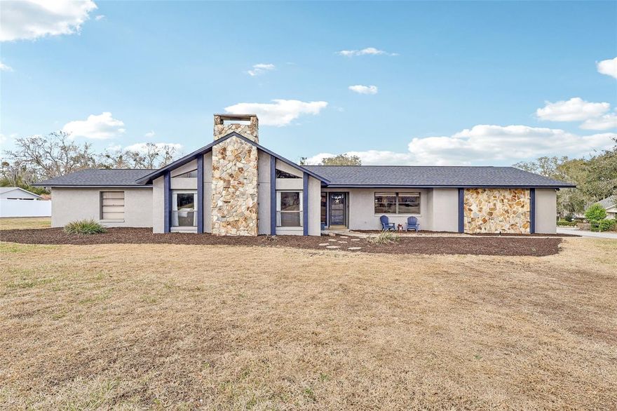 Architectural character and resort-style outdoor living come together on this beautifully maintained .43-acre corner lot located in a golf cart-friendly community with NO HOA. From the moment you arrive, the striking floor-to-ceiling stone chimney, bold architectural beams, and fresh exterior paint (2025) create standout curb appeal and give this home a custom feel you do not see every day. Inside, vaulted ceilings with exposed wood beams and a dramatic stone fireplace anchor the living space, while clerestory windows bring in natural light and enhance the open feel. Durable luxury vinyl plank flooring runs throughout the main living areas, offering the look of hardwood with easy maintenance and long-term durability. A built-in wet bar adds both function and personality, making the space ideal for entertaining. This is not a cookie cutter home. The architectural details and thoughtful layout set it apart from the typical floor plan. The split-bedroom design provides privacy, with an oversized primary suite offering generous closet space and an en-suite bath, while two additional bedrooms are positioned on the opposite side of the home near a full bath and laundry area. The kitchen features solid wood cabinetry, stainless steel appliances, a breakfast nook, and convenient access to the dining room for an easy flow. The backyard is a true highlight, featuring an impressive screened patio and pool enclosure with a fully pavered deck, multiple seating areas, and a covered lanai complete with ceiling fan and dedicated grilling space. The resurfaced gas-heated pool (2025) includes a new salt chlorination system (2025) and is connected to city gas for efficiency and convenience. Major updates include a new roof (2026), new pool screen enclosure (2026), exterior paint (2025), two AC units with one replaced (2017) and one replaced (2022), and a new drain field (2021). The oversized garage provides additional storage or workspace flexibility. With nearly half an acre, distinctive architectural detail, durable finishes, and extensive system upgrades, this home offers space, personality, and functionality in one complete package.