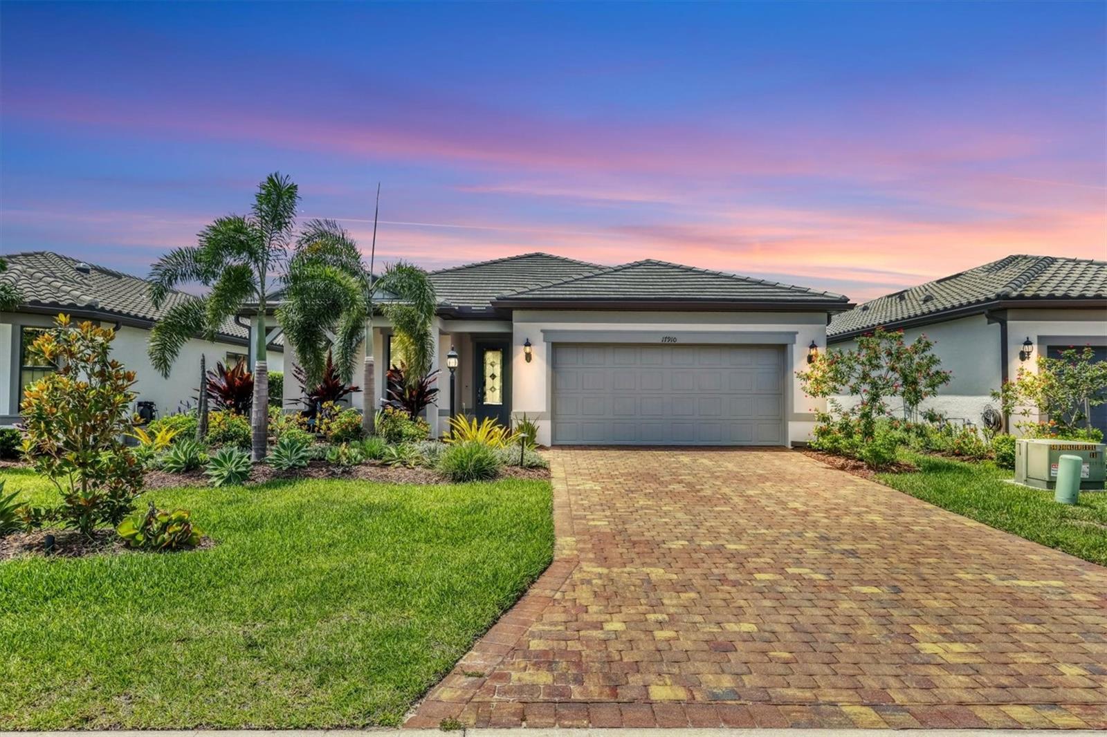 This nearly new, gently lived-in Mystique model in Del Webb Lakewood Ranch is ready now—and packed with thoughtful upgrades! Built in 2022, this pristine home offers a seamless blend of relaxed elegance, modern comfort, and privacy in one of the most sought-after 55+ communities in the region. Situated on a desirable south-facing homesite, you will thoroughly enjoy the private heated pool and spa, that creates a sunny backyard retreat. Lush tropical landscaping and a peaceful partial water view enhance the sense of tranquility and seclusion. The extended screened lanai provides ample space for dining, lounging, and entertaining under the Florida sky. Inside, the open-concept layout features expansive sliding glass doors—including a zero-corner slider—that connect the main living areas to the outdoors with ease. A sleek, modern gas fireplace serves as a stylish focal point in the great room, perfectly complementing the chef-inspired kitchen located just across the space. The kitchen is beautifully appointed with built-in stainless-steel appliances, a gas cooktop and vented hood, quartz countertops, soft-close cabinetry, under-cabinet lighting, and a generous walk-in pantry. Elegant wood-look porcelain tile runs throughout the main living areas, while plush carpeting in the bedrooms adds warmth and comfort. The home’s split floor plan includes three bedrooms and a versatile den enclosed by glass-paneled French doors, ideal as a home office, creative studio, or additional guest space. The primary suite offers a peaceful retreat with a tray ceiling and spa-style ensuite bathroom featuring a large, tiled walk-in shower, dual quartz vanities, a private water closet, and a walk-in closet. Tray ceilings are also featured in the main living area, adding architectural interest and height. Additional highlights include a fully outfitted laundry room with cabinetry and a utility sink, and a four-foot extended garage complete with epoxy flooring and a 220V outlet ready for your electric vehicle. Del Webb Lakewood Ranch offers a vibrant, amenity-rich lifestyle tailored for active adults. Residents enjoy world-class amenities, including six tennis courts, eight pickleball courts, bocce ball, a state-of-the-art fitness center with group classes, a resort-style pool, lap pool, neighborhood satellite pool, and an on-site restaurant and bar. A full-time Lifestyle Director curates a dynamic calendar of clubs, events, and social activities, all within a golf cart-friendly, gated community. Ideally located, Del Webb provides convenient access to Sarasota, Bradenton, Tampa, St. Petersburg, two international airports, and the award-winning Gulf Coast beaches. The nearby UTC shopping and dining district places boutiques, restaurants, and cultural attractions just minutes from your doorstep. Meticulously maintained and move-in ready, this exceptional home in the heart of Del Webb Lakewood Ranch offers the perfect opportunity to embrace Florida living without delay—schedule your showing today and move into a like-new home that’s ready to welcome you now.