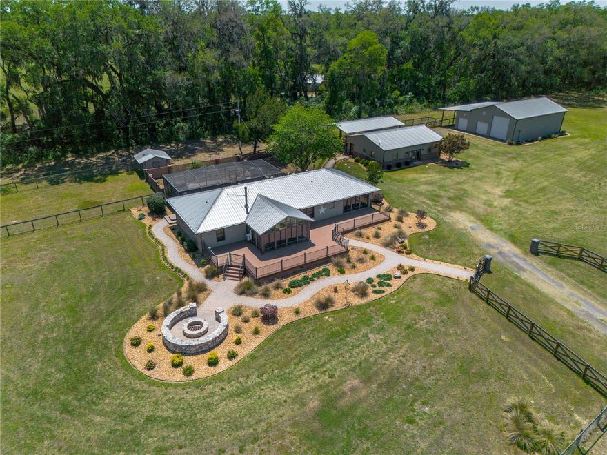 This is a must-see for any horse enthusiast seeking the perfect blend of privacy, beauty, and functionality. Welcome to a world where the rhythm of hoofbeats defines everyday life—an extraordinary 40-acre equestrian estate just minutes from town, yet worlds away from it all. Tucked behind a gated entrance and private drive, the property unfolds into sweeping, manicured pastures framed by majestic, mature oak trees—creating a setting that is both peaceful and inspiring. Fully fenced and cross-fenced with new fencing throughout, this farm is thoughtfully designed for breeding, training, or simply enjoying the equestrian lifestyle. An established agricultural exemption is already in place, and a private riding trail winds gracefully around the entire perimeter—offering the rare luxury of riding your own land every day. At the heart of the estate, the beautifully remodeled main residence spans 2,176 square feet and showcases warmth, craftsmanship, and intentional design. A charming paver walkway leads to a spacious deck and firepit—perfect for entertaining or unwinding under the stars. Inside, a light-filled sunroom, currently used as an office, offers flexible space for work or creativity. The kitchen blends elegance and function with granite countertops, stainless steel appliances, custom cabinetry, and a sink overlooking the lanai. The primary suite is a true retreat, featuring a farmhouse-inspired bath with a soaking tub and designer finishes. A versatile flex room with rich pecky cypress accents adds character and practicality, currently serving as a mudroom. Outdoors, the screened lanai with a full outdoor kitchen and gas grill creates the perfect setting for relaxed gatherings and enjoying the expansive views. Just steps away, a thoughtfully updated 1,200-square-foot cottage offers a private and inviting space complete with one bedroom, one bath, and a dedicated office. Beautiful details include tongue-and-groove ceilings, ceiling-height custom cabinetry, granite countertops, and a spacious kitchen island. The office features built-ins for seamless productivity, while the bathroom provides a spa-like experience with its own soaking tub. Adding even more flexibility, a charming 616-square-foot tiny home offers one bedroom and one bath—ideal for guests, staff, or income-producing potential. The main residence and cottage are both equipped with Generac generators, providing comfort and peace of mind year-round. The impressive main barn offers over 8,600 square feet under roof, featuring concrete aisles, a finished air-conditioned tack room with washer, two wash racks, and fans throughout for optimal airflow and comfort. A secondary cow barn provides over 3,000 square feet under roof with its own wash rack and additional A/C tack room. A separate two-stall horse barn with a metal roof, tack room, and nearby 720-square-foot storage barn adds even more versatility. The expansive 2,600+ square foot garage and workshop is perfectly suited for RV storage, horse trailers, and equipment, with multiple overhead doors and generous clearance. All barns are equipped with both power and water. Whether you're a dedicated rider, breeder, or simply seeking wide-open spaces paired with refined comforts, this rare offering delivers the ultimate place to live, work, and ride in perfect harmony. Conveniently located within 45 minutes of the World Equestrian Center in Ocala, with everyday essentials just minutes away, including Publix.