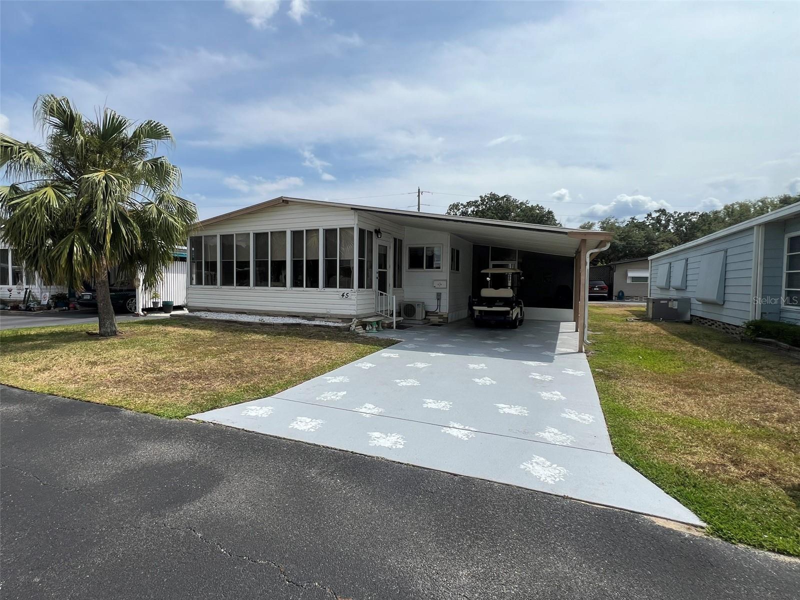 This spacious, move-in ready 2 Bedroom, 2 Bathroom manufactured home in the 55+ Floral Lakes Community in Bartow, Florida features a large U-shaped Kitchen with ample storage and breakfast bar, a Dining area with built in cabinetry and hutch, a large Living Room with sliding glass door that opens into the Florida Room with independent mini-split air conditioning/heating system (currently used as a third bedroom for guests). Primary Bedroom features dual closets plus a walk-in closet and en-suite bathroom with linen closet, dual vanities, and fiberglass shower enclosure with glass door. Guest bathroom features a tub/shower combo. Ceramic tile and wood laminate flooring throughout the home. Full size washer and dryer (included) are located in the utility room in the carport. Single car carport, plus covered and screened patio for outdoor living. Located in central Florida, between Tampa and Orlando, this golf cart friendly community is near the Bartow Civic Center, Bartow Public Library, and Mary Holland Park. Here you OWN YOUR LAND (no lot rent) and pay low monthly HOA fees. The Floral Lakes community offers access to a stocked pond with community boat ramp and dock. Clubhouse amenities include recreation space, shuffleboard, putting green, and large heated swimming pool. Social clubs, dances, exercise, pot lucks, and MORE! Association approval is required for purchase. Call your Realtor today for more information and to schedule a showing!