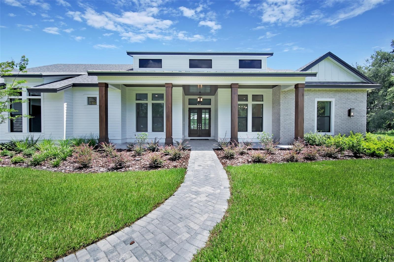 TUCKED AWAY AT THE END OF A QUIET COUNTRY ROAD AND BORDERED BY THOUSANDS OF ACRES OF CONSERVATION LAND, this brand-new modern farmhouse offers the perfect blend of luxury, comfort, and tranquility.
THE HOME: THIS SHOWSTOPPING RESIDENCE SHOWCASES EXCEPTIONAL CRAFTSMANSHIP AND UPSCALE FINISHES THROUGHOUT. Soaring ceilings, exposed beams, a 78” electric fireplace, and a decorative stone accent wall set the tone for warm sophistication in the heart of the home. The gourmet kitchen is a dream, featuring Monogram appliances, a six-burner gas range, double ovens, a microwave drawer, wine cooler, rich hardwood cabinetry, and a generous island perfect for entertaining or everyday living. Designed for both style and function, the split floor plan includes a spacious mudroom with a built-in family command center, durable engineered hardwood floors, and a large bonus room for extra flexibility.
Retreat to the serene owner’s suite, where a spa-like bath awaits with a freestanding tub, oversized walk-in shower, dual vanities, and a custom-designed closet complete with an 8-drawer center island. Three sets of sliding glass doors — including two corner sliders — open wide to a sprawling lanai with a fully equipped outdoor kitchen and a spectacular pool area. Whether hosting a crowd or enjoying a quiet evening, this space is designed for seamless indoor-outdoor living, featuring a sparkling pool with spa, sun shelf, and built-in seating.
THE LAND: STEP OUTSIDE AND IMMERSE YOURSELF IN NATURE — WITH DIRECT ACCESS TO OVER 11.5 MILES OF EQUESTRIAN AND HIKING TRAILS IN THE ALAFIA RIVER CORRIDOR NATURE PRESERVE. The 5± high-and-dry acres with room to roam, whether you’re envisioning horses or livestock, building additional structures, starting a garden, or simply enjoying the privacy. Located in a hidden pocket of Lithia known for custom homes and large-acreage estates, you’ll enjoy the peace of country living without sacrificing convenience. Top-rated schools, shopping, and dining are just a short drive away.