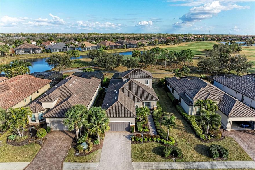 Located within the gated Esplanade Golf & Country Club at Lakewood Ranch, this rarely available and exceptionally upgraded Trevi floorplan offers the ultimate advantage for multi-generational living, with two primary suites, a separate area for guests or dedicated work from home office space. This home includes a coveted Golf Membership. Perfectly positioned near holes 2 and 17, the front of the home capture breathtaking water views with no homes directly in sight while the back offers landscaped berms and distant golf course views. Inside, the two-story design offers exceptional flexibility and thoughtful separation of space. The first-floor features wood-look laminate flooring throughout, a welcoming den or gathering room with water views, a separate dining area enhanced with a tray ceiling and designer wall panels, an open great room with sliders to lanai with new custom bar cabinetry featuring a 48-bottle dual-zone wine cooler and also 2 private bedroom suites ideal for guests or multi- generational living. The expansive primary suite offers a tray ceiling, views to pool area with new electric room darkening shades, spa-like bathroom with oversized shower and separate vanity areas, and a spacious newer custom closet and additional storage under stairs. The gourmet kitchen offers Cambria quartz countertops, Café stainless appliances, a newer GE refrigerator, natural gas cooktop, walk-in pantry with wood shelving, elegant pendant lighting, and sliders leading to lanai. A dreamy lanai frames a gas-heated, saltwater resort-style pool and spa with sun shelf and waterfall feature, complemented by a brand-new travertine deck. On one side of the lanai, a fully appointed granite outdoor kitchen showcases a built-in grill and griddle, newer ice maker, sink and plenty of storage, while the opposite wall features a custom built-in refrigerator and prep and entertaining station, together creating a private retreat designed for effortless hosting. Upstairs, two additional bedrooms share a bath and charming reading nook, plush carpeting, barn doors for complete privacy at staircase, and picturesque water and golf course views from every window create a serene retreat level. The light-filled interior, recently upgraded with modern energy-efficient recessed lighting, designer fixtures, plantation shutters, and new ceiling fans throughout. Additional features include a spacious laundry room, convenient powder bathroom, 8’ doors, and crown molding, while custom electric privacy shades enhance the living and kitchen spaces. The garage continues the elevated standard with an extended garage featuring epoxy-coated floors and new built-in storage closets. The owners of this home will enjoy a renowned 18- hole championship golf course, with additional resort style living amenities of tennis and pickleball courts, two fitness centers with an extensive calendar of classes, two resort-style pools, a full-service spa and salon, on-site dining at the Bahama Bar and Barrel House Bistro where live music, wine dinners, special events and fun holiday activities are part of vibrant social calendar, with landscaping maintenance included in HOA fees.  Situated just moments from local town centers, parks, UTC, award winning Gulf Beaches, and convenient access to airports I the #1 Selling community in the U.S. In a fully built-out, established neighborhood, this move-in-ready residence presents an elevated lifestyle at an extraordinary value.