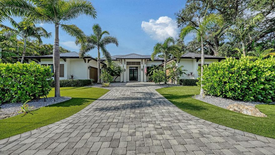 Located West of Trail near the historic Field Club, this stunning residence is a refined interpretation of British West Indies architecture,
 offering over 4,000 square feet of thoughtfully designed single-level living. Set on an estate lot, the home blends timeless coastal elegance with exceptional craftsmanship and seamless indoor–outdoor flow. A dramatic great room welcomes you with vaulted wood ceilings, fireplace, and expansive pocketing sliders that frame views of the lushly landscaped pool and spa. The open-concept design flows effortlessly into the chef’s kitchen, appointed with premium Thermador and Wolf appliances, custom solid-wood cabinetry, quartz surfaces, and an oversized island—perfectly complemented by a separate dining area and custom dry bar with wine refrigeration. Designed for both privacy and versatility, the residence features four en-suite bedrooms, office, and a spacious TV lounge or bonus room that opens directly to the outdoor living areas. The private primary suite is a serene retreat with a vaulted wood ceiling, dual walk-in closets, and direct access to the covered lanai. Its spa-inspired bath showcases dual vanities, a soaking tub, and an expansive glass-enclosed shower. Outdoor living is a true centerpiece, with a generous travertine lanai, fully equipped outdoor kitchen, dining verandah, and a large gas- and electric-heated saltwater pool and spa with waterfall—ideal for entertaining or quiet relaxation amid tropical landscaping and architectural lighting. Additional highlights include hurricane-rated impact windows and doors, a whole-house generator, brand new metal roof, dual on-demand water heaters, an expansive paver motor court, low maintenance yard, and a rare four-car garage configuration, including an owner’s garage with EV outlet and climate control. Ideally located minutes from Siesta Key, Southside Village, Sarasota Bay, and downtown Sarasota, this exceptional home offers privacy, design integrity, and proximity to the best of the Sarasota lifestyle