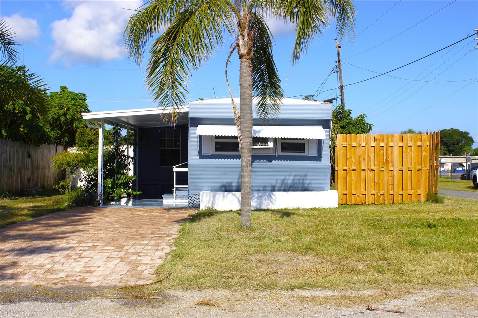 Updated mobile home on a corner lot in Bonita Village! 2 bedrooms, 1 bathroom, screened lanai, carport, and fenced backyard. Freshly paved driveway leads to a covered carport and front entrance. Inside, the open living/dining/kitchen layout offers bright, functional space. Kitchen features new cabinets, granite-look Formica counters, tile backsplash, new appliances, and ample storage. Bathroom includes a new tub and upgraded vanity. Vinyl laminate flooring throughout, plus new windows, doors, AC wall units, LED lighting, and fresh interior/exterior paint. Screened lanai with paver flooring and laundry area opens to a spacious wood-fenced backyard. New water heater and septic tank installed ~2 years ago. No carpet. No flood insurance required. HOA fee includes trash remobal. Convenient for shopping, dining, parks, Sponge Docks, and beaches. Clean, updated, and move-in ready!