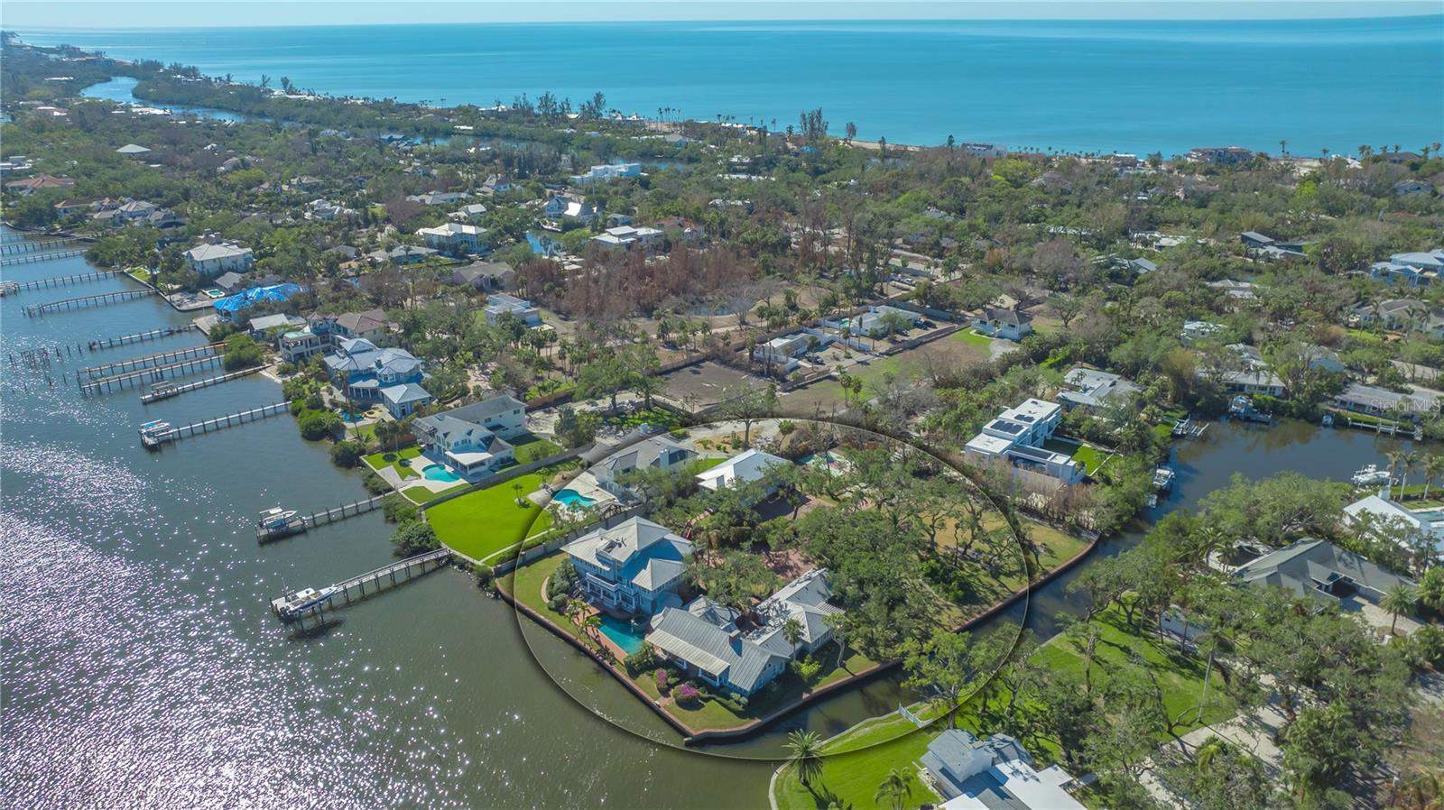 This extraordinary waterfront property offers an unparalleled opportunity to create a stunning retreat overlooking the tranquil waters of Little Sarasota Bay. Spanning over 1.5 acres, this expansive corner parcel boasts more than 500 feet of water frontage on two sides, providing exceptional privacy and sweeping coastal views. Situated within the exclusive Sanderling Club on Siesta Key, this unique property is poised for transformation. The existing six-bedroom home offers a canvas ready for designing your custom dream residence. The main house includes formal living and dining rooms, an eat-in kitchen, family room, media room, and multiple dens. The first level features three bedroom suites, while the primary suite occupies the second floor with an additional guest suite and a bonus room. The third level houses another flexible space, ideal for a den or home office. A four-car split garage, connected by a courtyard, includes a studio apartment with a bedroom suite and guest kitchen, offering potential for guest accommodations or a private workspace. The outdoor spaces are equally expansive, featuring an open pool deck, fountain, waterfront lounge areas, winding walkways, and basketball court. With over 500 feet of waterfront access, boating enthusiasts will appreciate the ample opportunities to enhance this property with custom docks or lifts. Nestled in the prestigious Sanderling Club, this property combines the charm of Siesta Key’s coastal lifestyle with the exclusivity of a gated community. The Sanderling Club, the only guard-gated, single-family neighborhood on Siesta Key, offers residents access to a renovated clubhouse with a catering kitchen and library, three Har-Tru tennis courts, playground, and deeded access to a pristine stretch of Siesta Beach. Located minutes from Siesta Village, this property provides the perfect balance of serene seclusion and proximity to Sarasota’s vibrant cultural and culinary attractions. This is a once-in-a-lifetime opportunity to design a coastal sanctuary in one of Sarasota’s most coveted neighborhoods.