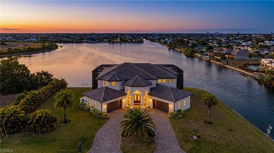 Welcome home to 2003 NE 10th Place in Cape Coral, a custom freshwater lakefront estate on Lake Meade that showcases true luxury living! Built with Insulated Concrete Form construction found in less than 1% of Cape Coral homes, this residence is engineered for Florida with exceptional storm resistance, impressive energy efficiency, and long-term durability. A hurricane rated tile roof was installed in 2023, full impact windows eliminate the need for shutters, and a 48kW whole home automatic generator system was added in 2025. Designed for comfort, the home features multiple newer (2024-2025) A/C systems with dedicated zoning including separate systems all paired with Wi Fi enabled smart thermostats. Professional smart home features include a whole home Lutron lighting control system, integrated security with cameras and smartphone monitoring, Wi Fi MyQ garage openers, and a professionally installed Tesla 50 amp Level 2 EV charger. This is a property where lighting, climate, pool, security, and garage systems are designed to work together for modern, elevated living. Outdoor living is the showstopper with a two-story screened lanai capturing expansive lake views, dual balconies, and a resort style saltwater pool and spa powered by the newest generation Pentair remote controlled system. Enjoy energy efficient heating via a heat pump and manage pool and spa heating, lighting, and settings from anywhere. The ground level offers an oversized entertaining area overlooking the water, while the full width upper balcony delivers a stunning 180 degree lake panorama. On the waterfront, a jet ski lift is already in place, and the freshwater setting offers lower corrosion and maintenance than saltwater canals, plus seawall and dock ready infrastructure. Nearby Mead Park has been approved for construction. And NO FLOOD ZONE. On nearly a half-acre corner lot with southern rear exposure, this home offers extra privacy, all day sun on the pool, and no HOA fees. Inside, the layout is ideal for luxury buyers and investors alike with 5 bedrooms and 5 full bathrooms including 4 true primary style suites perfect for multigenerational living, extended guests, or flexible rental strategies. A gourmet kitchen anchors the home with a large island, stone counters, custom soft close cabinetry, and brand new stainless appliance package, complemented by high ceilings, cove lighting with new multi color LED, and tile flooring that has been professionally maintained. Rarely does Cape Coral offer this level of build quality, automation, flexibility, and waterfront lifestyle in one address. With incredible lake views and a true four-car garage that includes a climate-controlled flex bay, this home stands out in every way. It has also performed as a successful vacation rental, making it an exceptional choice as a dream waterfront estate or a high-end investment, 2003 NE 10th Place stands out as THE opportunity in the freshwater luxury market.