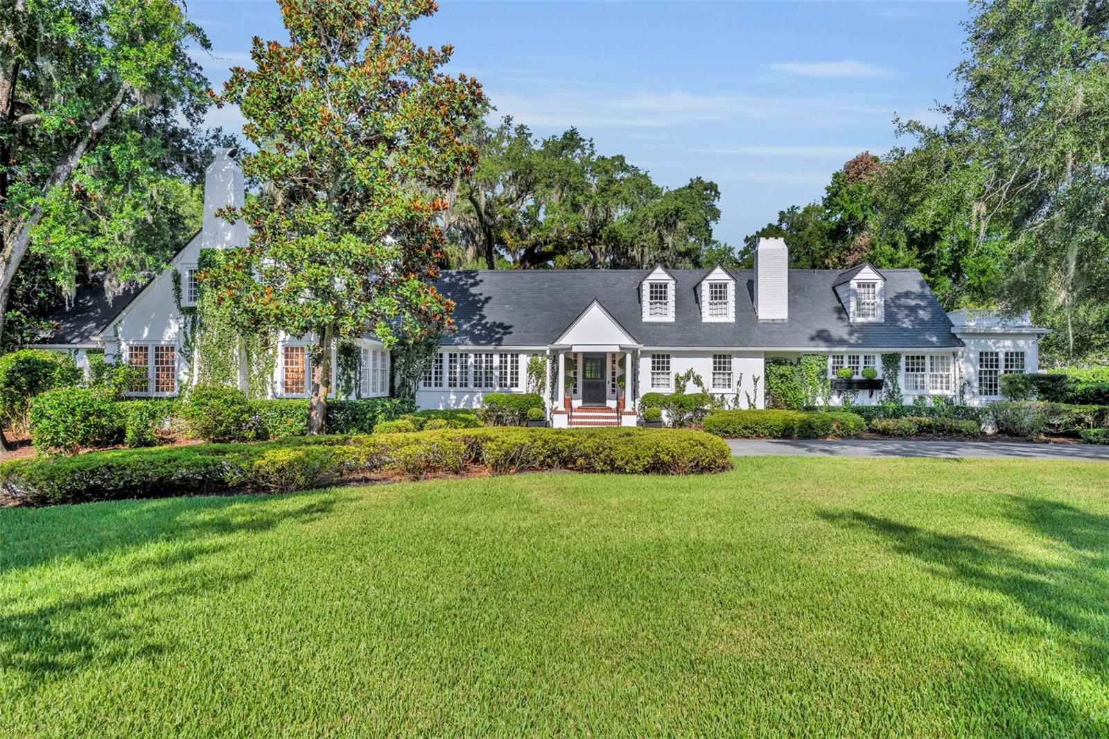 Offered for the first time in over 50 years, this distinguished Winter Park estate is a true traditional gem, nestled on a picturesque brick street and situated on a full 1-acre lot. Exuding timeless charm with a subtle New England ambiance, this residence represents the best of historic Winter Park living—all within walking distance to Park Avenue.
This stately 6-bedroom, 5.5-bathroom home offers 5,759 square feet of thoughtfully designed living space, plus an additional 1,859-square-foot unfinished basement that spans the entire length of the home, offering endless possibilities for expansion or customization.
Upon entry, you'll be welcomed by coffered ceilings in the spacious formal living room, rich dark oak floors, and one of the home’s three gas fireplaces. This elegant yet inviting room overlooks the lush gardens, making it an ideal setting for both entertaining and quiet relaxation.
Adjacent to the living room is a cozy, beautifully appointed den featuring another gas fireplace and natural jute flooring—undoubtedly one of the most beloved spaces in the home.
The kitchen is filled with natural light and includes a large casual dining area, a charming butler’s pantry, and direct access to both the laundry room—complete with a full-size refrigerator and half-bath—and the oversized 2-car garage.
The formal dining room showcases lattice-framed bay windows with views of the back garden and pool area, creating a warm and elegant space perfect for holiday dinners and family gatherings.
The home features two primary bedroom suites on the main level, including one expansive L-shaped suite with its own gas fireplace and views of the pool, gardens, and outdoor terrace. The primary bathroom includes a dressing area and marble finishes throughout.
Upstairs, the south wing includes two generous bedrooms with a shared full bathroom, while the north wing—located above the kitchen—offers two additional bedrooms and a charming full bath.
The expansive backyard is a private sanctuary, framed by majestic oak trees, bamboo, and thoughtfully designed gardens, with several inviting sitting areas for outdoor relaxation. An extra-large swimming pool completes the setting—perfect for warm Florida days or evening gatherings under the stars.