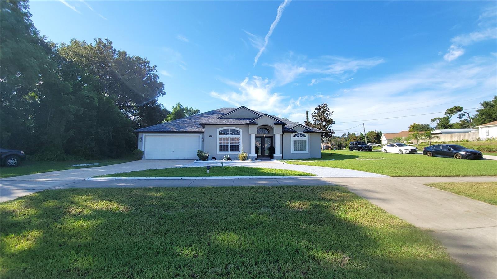 DELTONA: This beautifully maintained 3-bedroom, 2-bath home sits on a desirable corner lot and offers exceptional curb appeal. Featuring a split-bedroom, open floor plan with high ceilings, this home feels spacious and inviting from the moment you step through the elegant French front doors. Recent updates include modernized bathrooms, updated flooring, and a freshly painted interior in tasteful, decorative colors. The large circular driveway adds convenience and charm, while the 2-car garage provides ample storage or parking. Enjoy outdoor living on the expansive deck out back, perfect for entertaining or relaxing. Additional highlights include a tankless water heater ensuring energy efficiency, and a roof replaced just two years ago, offering peace of mind for years to come. Conveniently located near shopping, restaurants, and schools, this home combines comfort, style, and practicality in one desirable package.