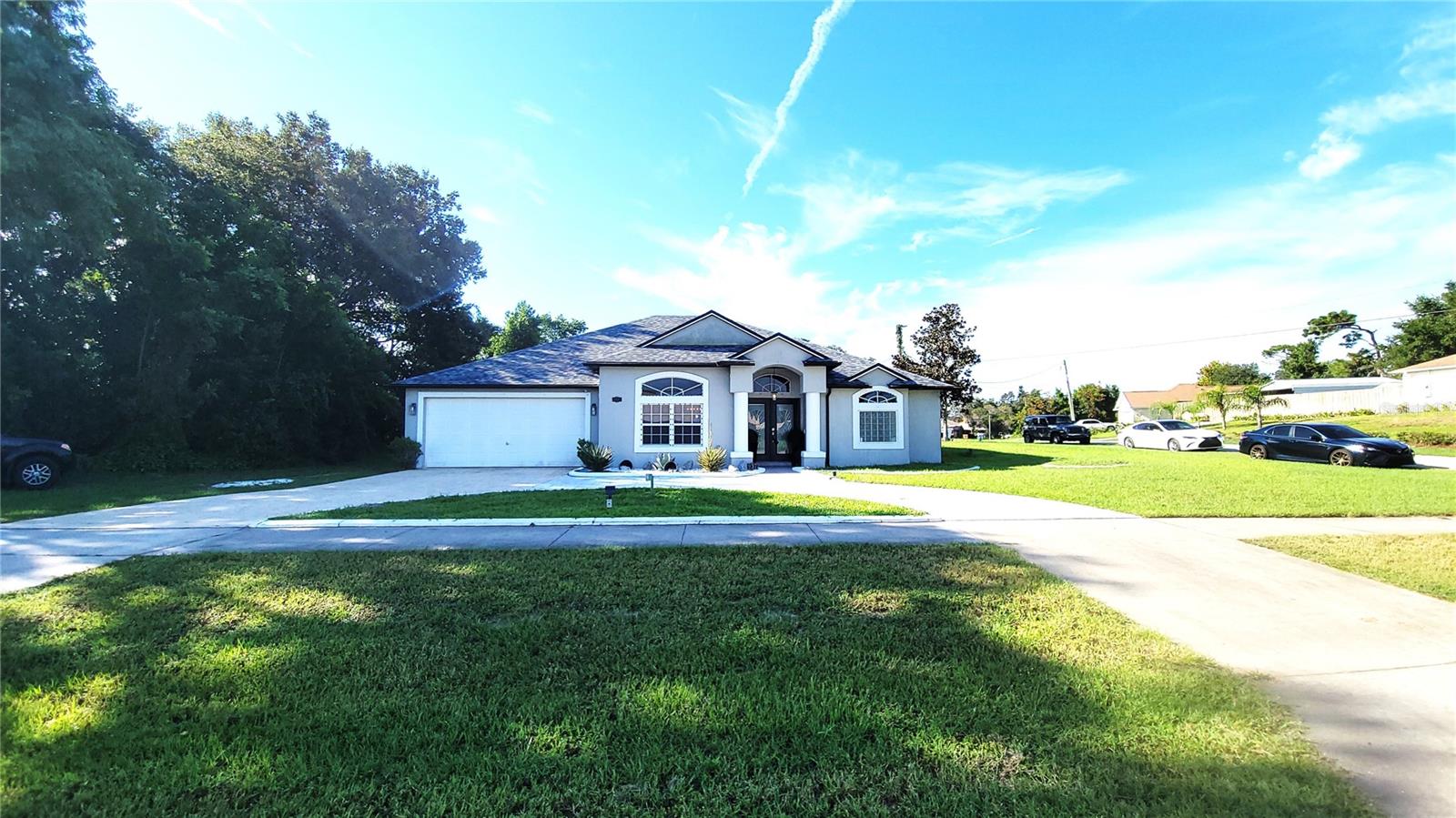 DELTONA: This beautifully maintained 3-bedroom, 2-bath home sits on a desirable corner lot and offers exceptional curb appeal. Featuring a split-bedroom, open floor plan with high ceilings, this home feels spacious and inviting from the moment you step through the elegant French front doors. Recent updates include modernized bathrooms, updated flooring, and a freshly painted interior in tasteful, decorative colors. The large circular driveway adds convenience and charm, while the 2-car garage provides ample storage or parking. Enjoy outdoor living on the expansive deck out back, perfect for entertaining or relaxing. Additional highlights include a tankless water heater ensuring energy efficiency, and a roof replaced just two years ago, offering peace of mind for years to come. Conveniently located near shopping, restaurants, and schools, this home combines comfort, style, and practicality in one desirable package.