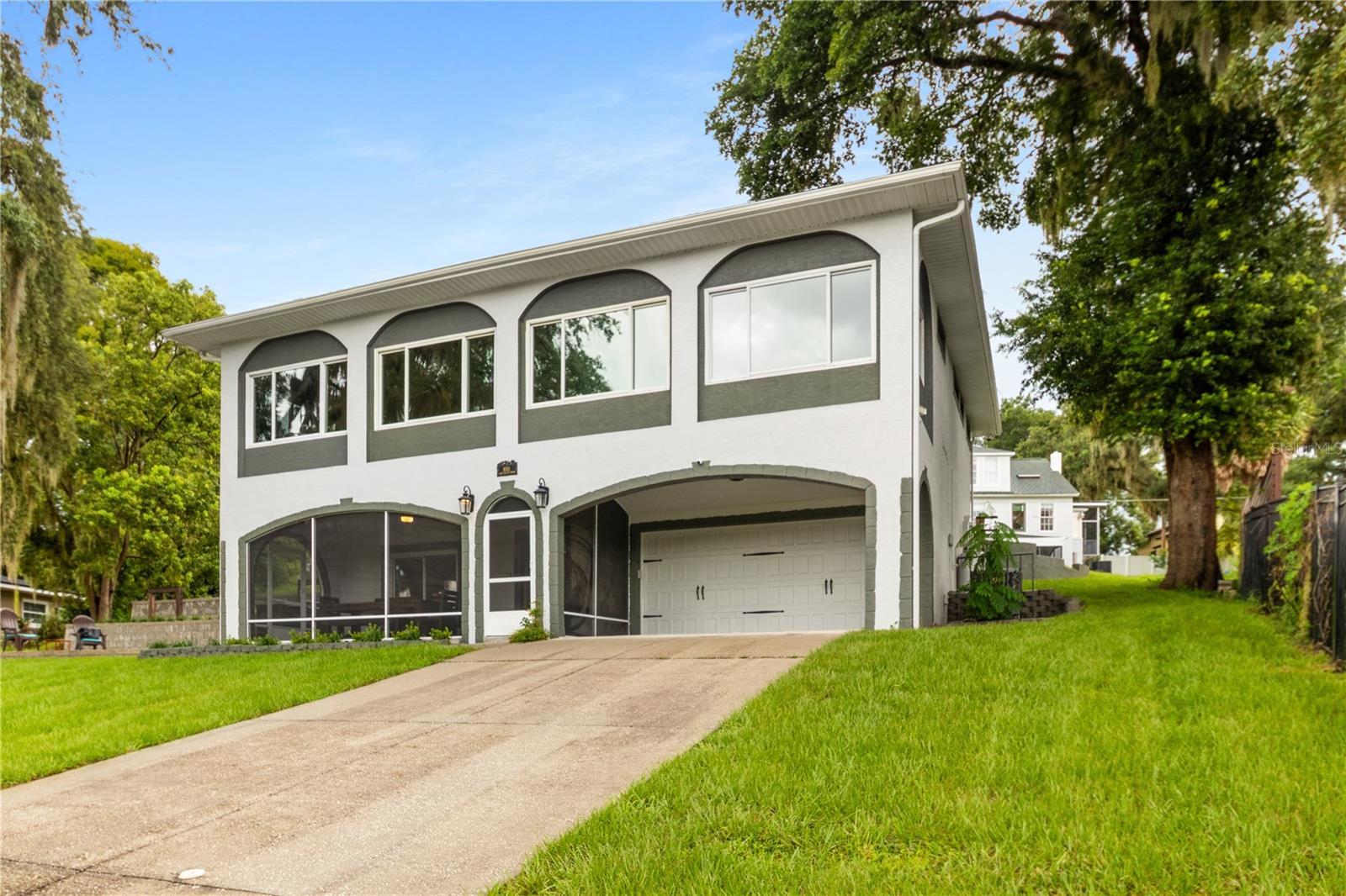 This stunning smart home combines modern elegance with cutting-edge technology, all while offering breathtaking views of Lake Gracie. From its stately front entrance to the circular drive at the rear, this home is designed for both beauty and convenience. The lower-level lakeside entrance welcomes you to a serene retreat, while the upper-level entrance, accessible via the circular drive, leads directly into the heart of the home. Every inch of this property has been meticulously transformed, leaving no detail overlooked. The home boasts newer windows, a state-of-the-art AC system, luxury wood-like vinyl flooring, crown molding, shiplap accents, and a beautifully updated banister. The kitchen is a chef’s dream, featuring stainless-steel appliances, granite countertops, and a cooking island with a breakfast bar. The enclosed veranda and expansive family room are perfect for soaking in the lake views, while the gas fireplace adds a touch of romance to the open, light-filled living spaces. The upper level is thoughtfully designed for modern living, with two spacious bedrooms, a stylish bathroom with a tub and shower, and an open-concept layout that maximizes the stunning water views. Downstairs, the ground level is home to the luxurious primary suite, complete with a spa-like ensuite bathroom featuring a large walk-in shower, double granite sinks, and high-end finishes. This level also includes a laundry room, a workshop, a screened front porch, and an oversized garage with EV-ready capabilities, a remote-access opener, and a pull-down workbench. As a fully equipped smart home, this property offers smart light switches in every room, a comprehensive security system with cameras and motion sensors, programmable window treatments, automatic entry lights, and a remote-access audio system. Additional features include a Murphy bed in the spare bedroom and new garage flooring.Move-in ready and truly one of a kind, this home is a perfect blend of style, functionality, and innovation, all set against the picturesque backdrop of Lake Gracie.
