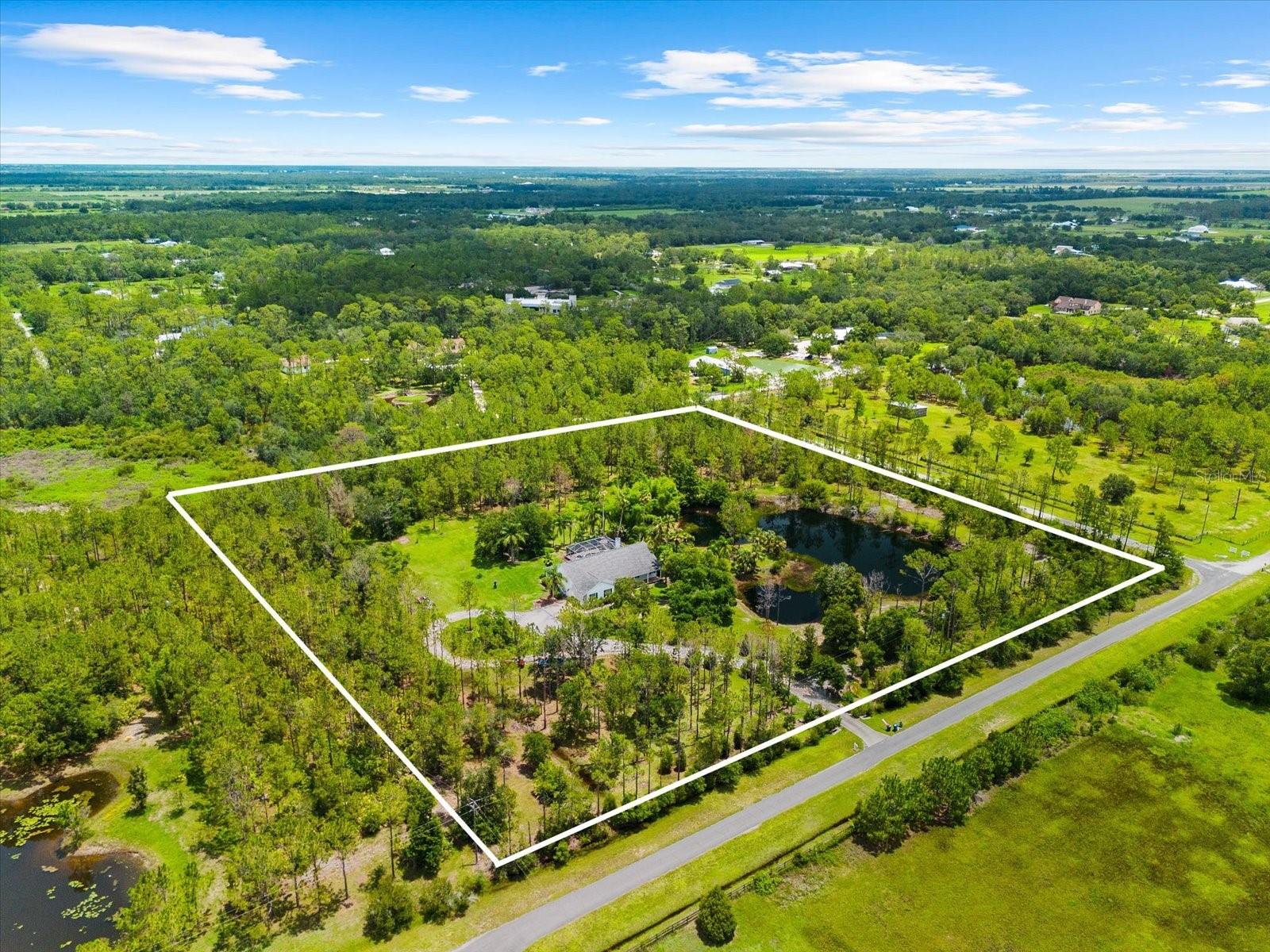 Incredible Opportunity in Panther Ridge.... Welcome to your own private retreat on over 9 acres in the heart of Manatee County’s most sought after equestrian community. Tucked away at the end of a quiet street, this beautiful property offers the peaceful lifestyle so many dream of, with room for chickens, cows, horses, and even future expansion with up to three total structures permitted including barns or workshops with HOA approval. Custom built by Cahill Homes, this three bedroom plus den, two bath residence is ideally positioned on one of the largest spring fed lakes in Panther Ridge. From nearly every angle, you will enjoy breathtaking views and frequent visits from deer, cranes, eagles, turtles, and more. The home has been tastefully updated and thoughtfully maintained, featuring a popular great room layout with vaulted ceilings, a skylight, a cozy brick fireplace, and a formal dining area as well as a spacious breakfast nook with oversized windows that bring the outdoors in. The chef’s kitchen boasts solid wood cabinetry, stainless steel appliances including a double convection oven, granite countertops, and vinyl plank flooring throughout the main living spaces. The owner's suite includes sliding doors to the pool area, a generous walk in closet, and a luxurious spa style bath with a Roman walk in shower and soaking tub. Outdoors, unwind on the travertine pool deck under a tongue and groove wood ceiling lanai. The saltwater pool and spa overlook the lake, where you can fish, canoe, or simply relax on your own private beach. Follow the walking trail through native cypress, pine, and oak trees and gather around the firepit for peaceful evenings under the stars. Sunrise and sunset views reflect beautifully across the always full lake, which is stocked with tilapia.
Additional highlights include an extra deep 20 by 28 side entry garage, a full laundry room, and a variety of fruit trees planted around the property. Recent upgrades include a new roof in 2018, a solar powered automatic driveway gate, upgraded gig speed internet, a new washer in 2022, new pool heater 2024, two new AC systems in 2024, brand new garage door 2024, reverse osmosis water system, and conversion of the pool to a salt system. Residents of Panther Ridge enjoy a neighborhood park with sports fields, a horse only area, basketball court, and playground. Miles of scenic trails for hiking and riding offer a sense of true country living, while nearby Lakewood Ranch brings shopping, dining, and top rated schools just minutes away. Sarasota’s renowned beaches, St Pete, and Tampa are also within easy reach. Whether you are looking for a tranquil personal homestead, space for animals, or a forever home surrounded by nature, this special property offers a rare blend of privacy, convenience, and character.