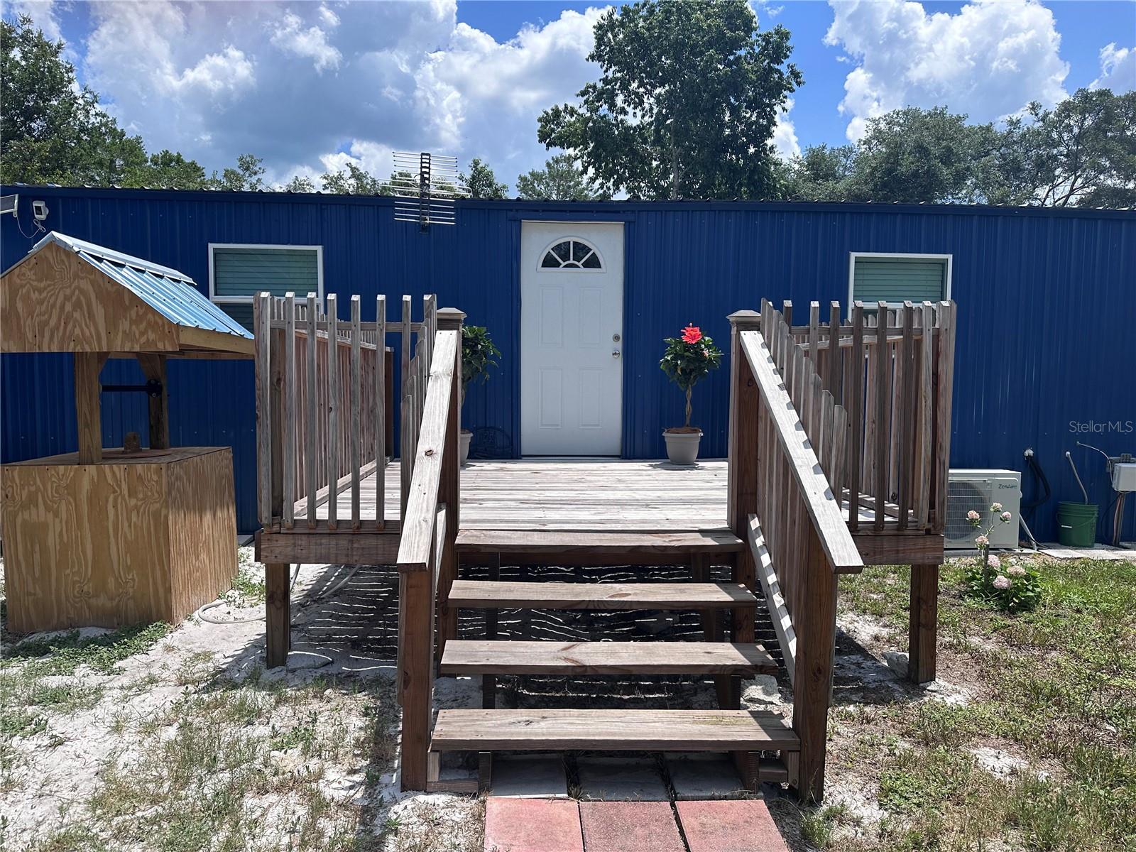 Imagine a rural, rustic home in Paisley, Florida, that is a cozy, completely renovated mobile home that’s bursting with countryside character. Nestled on a half-acre lot, this two-bedroom, one-and-a-half-bath beauty welcomes you with a sturdy 5-foot fence draped in privacy screen fabric, giving it that secluded, down-home feel. Pull up, and you’re greeted by a spacious wooden deck, perfect for sipping sweet tea at sunset. Step inside, and the open floor plan pulls you right into a warm family room, blanketed in weathered-look vinyl plank flooring and soft, earthy tones. A big ol’ window lets golden light spill in, giving the space a cozy glow. The kitchen—oh, it’s a showstopper! A massive granite-topped island sits proud in the center, begging for homemade pies or late-night chats with friends. There’s heaps of storage tucked underneath, plus a stainless steel sink with a view of the sprawling backyard. Down the hall, a roomy guest bath doubles as a laundry space, decked out with a sliding barn door that screams rustic chic. The primary bedroom is a peaceful retreat, with windows inviting in that warm Florida sunshine and an en-suite bathroom boasting a full shower and built-in cabinetry. Across the way, the second bedroom’s got a hefty built-in desk and shelving, plus its own sliding barn door for that extra touch of country flair. Out back, a sturdy deck leads to a massive, 24wx40lx12h steel RV/carport sitting pretty on a 6”concrete slab with rolled wire, with a car lift for all your tinkering needs!! There’s a big storage shed, a lean-to, and even a poured concrete block safe room for peace of mind. This half-acre spread’s got plenty of room for gardening, farming, or stashing your treasures, making it ideal for automotive buffs, homesteaders, or artisans looking to create. Home also has a full security system!! This quiet slice of country paradise blends modern updates with that soulful, rural vibe—definitely a spot worth visiting to soak in its charm!