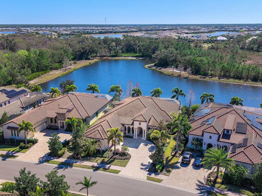 Welcome to 16818 Berwick Terrace, an exceptional Cardel Homes masterpiece tucked away at end of a quiet, sheltered cul-de-sac. Spanning nearly 3,700 square feet, this coastal-inspired residence exemplifies refined elegance and superior craftsmanship within the gated golfing community of Country Club East in Lakewood Ranch. This stunning single-story home showcases uninterrupted panoramic lake views, framed by lush landscaping and abundant wildlife, where waterfowl glide across the water and birds fill the air with song, creating a peaceful, private sanctuary. Glass entry doors open to a thoughtfully curated interior featuring travertine marble flooring and engineered hardwood flooring in all common areas including the primary suite, setting the tone for timeless luxury. At the heart of the home, the gourmet kitchen impresses with high-end appliances including Wolf and Monogram, rich wood cabinetry, and an expansive stone island that doubles as a breakfast bar, seamlessly flowing into the casual dinette and great room. The great room’s soaring ceilings and disappearing sliding glass doors blur the lines between indoor and outdoor living, ideal for entertaining or relaxing. Additional living spaces include a bonus room for leisure, a private den or office near the entry, and a climate-controlled custom wine room with capacity for over 700 bottles, a showpiece for the connoisseur. The luxurious primary suite is a private retreat, offering a spacious walk-in closet and a spa-inspired en-suite bath with a soaking tub, glass-enclosed walk-in shower and dual split stone vanities. Two generously appointed guest suites, each with walk-in closets and Jack and Jim bath, provide comfort and privacy for family and visitors. Go outside to a resort-style oasis designed for the ultimate Florida lifestyle. Enjoy a heated saltwater pool and spa, a spacious covered loggia and a full outdoor kitchen, all overlooking serene lake views that complete this exceptional setting. Notable upgrades include a spacious laundry room, extensive custom storage cabinetry from the 3.5-car garage, a whole-house generator, motorized hurricane screens in the lanai, whole-house surge protection, dual HVAC systems with UV lights, tankless water heater, accordion storm shutters, tray ceilings, lush landscaping with accent lighting and elegant crown molding, enhancing beauty and functionality. This is more than a home, it’s an elevated living experience. Residents of Country Club East enjoy a resort lifestyle with access to three community pools, including The Retreat, featuring a resort-style pool, fitness center, social spaces, outdoor kitchen and scenic nature trails, all included with HOA fees. Optional memberships are available at the Lakewood Ranch Golf and Country Club, offering golf and social amenities. Ideally near shopping, dining, A-rated schools, cultural venues and world-renowned beaches, this exceptional residence invites you to indulge in the lifestyle you deserve.