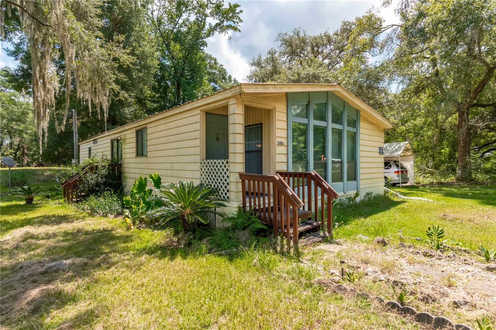 Welcome to Hidden Gem Farm, nestled at the heart of NW Ocala’s celebrated Horse Country, this 5-acre property offers a park-like setting that blends privacy with natural beauty. A rare find set amongst beautiful horse farms, the property has an ideal location just 2.2 miles from HITS and 10.3 miles from the World Equestrian Center (WEC). A private, tree-lined drive features two separate solar/electric powered automatic entry gates, and the property is fully fenced and cross-fenced with post and no-climb wire fencing. A large fenced paddock, which could easily be split into more paddocks, is established at the rear of the property, ready for horses to call it home. There are currently 2 homes on the property, each with their own addresses, separate wells and septic systems. The primary residence is a 3-bedroom, 2-bath, 1,583 sq. ft. doublewide mobile home that offers an open layout and ample living space. While built in 1984, the home was relocated and updated in 2005, including new flooring, paint and more. A metal roof and 2024 water heater add extra peace of mind, while features like a spacious kitchen, multiple living areas, and a 337 sq.ft. screened-in patio make it a comfortable place to entertain and call home. The patio also features a ramp walk-way entry, making the home even more accessible. The entire property is incredibly beautiful and offers gentle shade from mature oaks and a variety of other mature trees, with many clear areas that would be well-suited for further customization like a barn or other structures as needed. There are a variety of nearby equine service providers, tack and feed retailers, veterinary care, and everyday amenities, making it an ideal option for convenience. This property is a dream as it provides the flexibility to meet all the needs of Equestrians who want to be close to the AMAZING horse amenities or for anyone looking for privacy, and the space to enjoy nature at its best. This is a unique and one of a kind find that shouldn’t be overlooked!