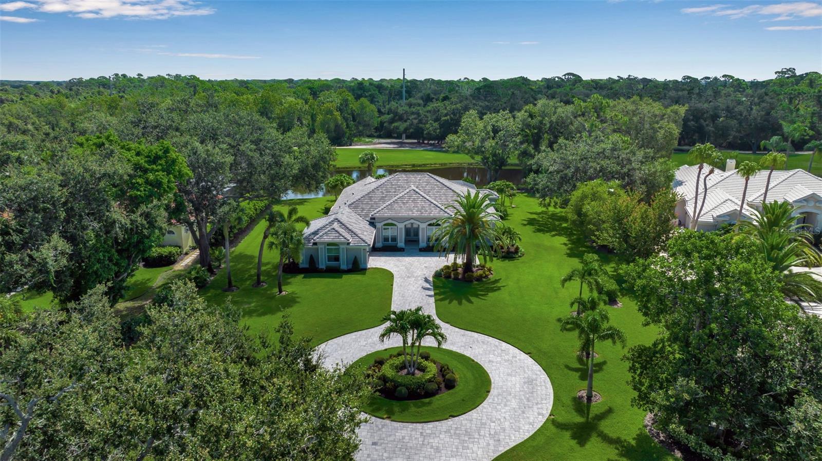 This completely remodeled home in The Oaks Clubside, set on nearly an acre of mature, meticulously landscaped grounds, is pure perfection. Nestled behind the gates of The Oaks Clubside, this residence is a masterful blend of classic elegance and contemporary sophistication. Arriving at the property, you are greeted by a striking full-circle driveway—a graceful approach that not only enhances the home’s curb appeal but also provides abundant guest parking for social gatherings and celebrations with loved ones. Step through the double front doors, with leaded glass, and you will immediately be taken by the clean lines and modern elegance of this home. The floors throughout the main living area are wood-look tile, making for beauty as well as ease of maintenance. The numerous high ceilings, windows and doors make the entire interior open, light and airy. With three generously sized bedrooms, an office or den, and two and a half baths, the layout adapts effortlessly to a variety of needs. The open floor plan ensures that each room enjoys picturesque views of the private lot, blurring the boundaries between indoor comfort and the natural beauty outside. The open kitchen will delight any home chef with its high-end stainless steel appliances, wide expanse of quartz countertops, an abundance of cabinetry for storage and a breakfast bar. There is a cozy breakfast nook, with a gorgeous outdoor view, for causal meals, and a formal dining room. The master suite is a study in luxury. This bright, spacious retreat features an incredible bathroom with a sunken tub and huge separate shower. The entire outdoor space has been thoughtfully updated, with ample areas for lounging, dining, and entertaining. The inviting pool and spa beckon you to cool off on a sunny afternoon or unwind beneath the stars. The new sleek pool cage ensures you can enjoy the outdoors in comfort, with incredible views. This home boasts a host of recent upgrades designed to provide ultimate comfort and efficiency. Impact windows and doors offer storm protection and energy savings while letting in abundant light. A new roof adds to the peace of mind, ensuring years of worry-free living. Add to all this, a large laundry room, a big, clean garage, custom lighting, plantation shutters, a gorgeous fireplace and so much more, and you have discovered the perfect home for living ultimate country club lifestyle on the Gulf Coast. The Oaks, Sarasota’s premier golf and country club, has two championship golf courses, an outstanding tennis program, pickle ball and croquet courts, a junior Olympic community pool, state-of-the-art fitness center and offers a wide variety of dining, recreational and social options. Membership is required with homeownership.