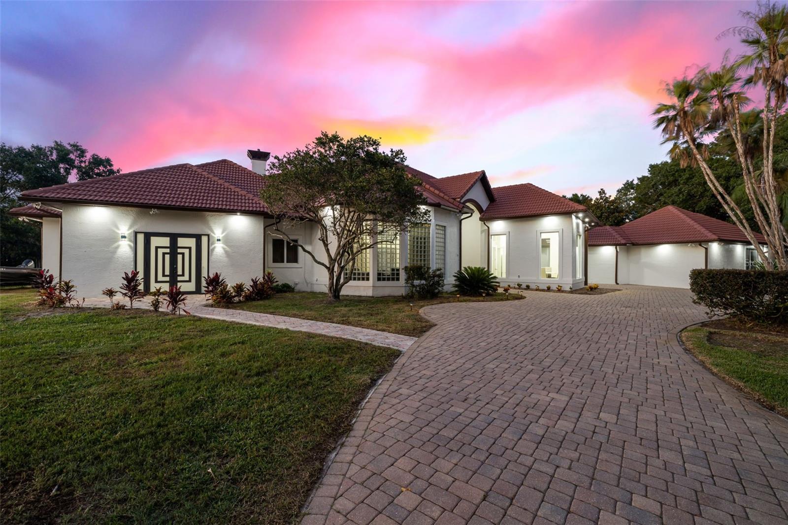 PRICE IMPROVEMENT! Welcome to Tiffany Lake Manors, where luxury living meets serene waterfront bliss. This newly modernized, lakefront estate offers 4 bedrooms, 3.5 bathrooms, a 3-car garage with a dedicated workshop, and an expansive 5,220 sq. ft. of elegant living space all situated on a private 2.5-acre gated lot with 180° unobstructed water views. Step through your custom double-entry impact glass doors into a home designed to impress, featuring wood-look porcelain tile throughout and thoughtfully curated high-end finishes. The chef’s kitchen boasts a 6-burner gas cooktop, quartz waterfall countertops, KitchenAid appliances, a built-in refrigerator, undermount farmhouse sink, coffee bar, and walk-in pantry with space for a second refrigerator. Stone accent walls and abundant natural light create a perfect blend of rustic elegance and modern design.The primary suite is your personal sanctuary, with a private sitting area, two massive walk-in closets with islands, LED lighting, and a spa-inspired en-suite featuring a freestanding slipper tub, dual rainfall shower heads, multiple body jets, and touch-activated brass fixtures. Adjacent is a dedicated home gym overlooking the lake for the ultimate in wellness convenience. Multiple entertaining spaces include a family room, a separate living room with vaulted ceilings and a sleek modern fireplace. At the back of the living room is a wet bar that opens to the resort-style screened pool area. Outdoors, enjoy your screened in heated saltwater pool with brick paver decking, a fire pit lounge area, and a covered lanai – all overlooking your private dock on a kayak and fishing-friendly lake. The secondary bedrooms offer privacy and comfort — including a guest suite with a private bathroom and additional bedrooms sharing a stylish Jack-and-Jill bath, all with rainfall showers, vessel sinks, and high-end fixtures. All bathrooms feature touchless ANZZI bidet toilets with advanced features. Additional highlights include: New A/C (2023) & all-new ductwork (2020), Impact glass block architectural accents, Fully fenced and gated property, Smart home touch-activated faucets throughout, Generac home generator. This showpiece home offers resort-style living with privacy, luxury, and unmatched lake views while still offering easy access to Downtown Tampa and all it has to offer. Don’t miss your opportunity to own this one-of-a-kind Florida estate!