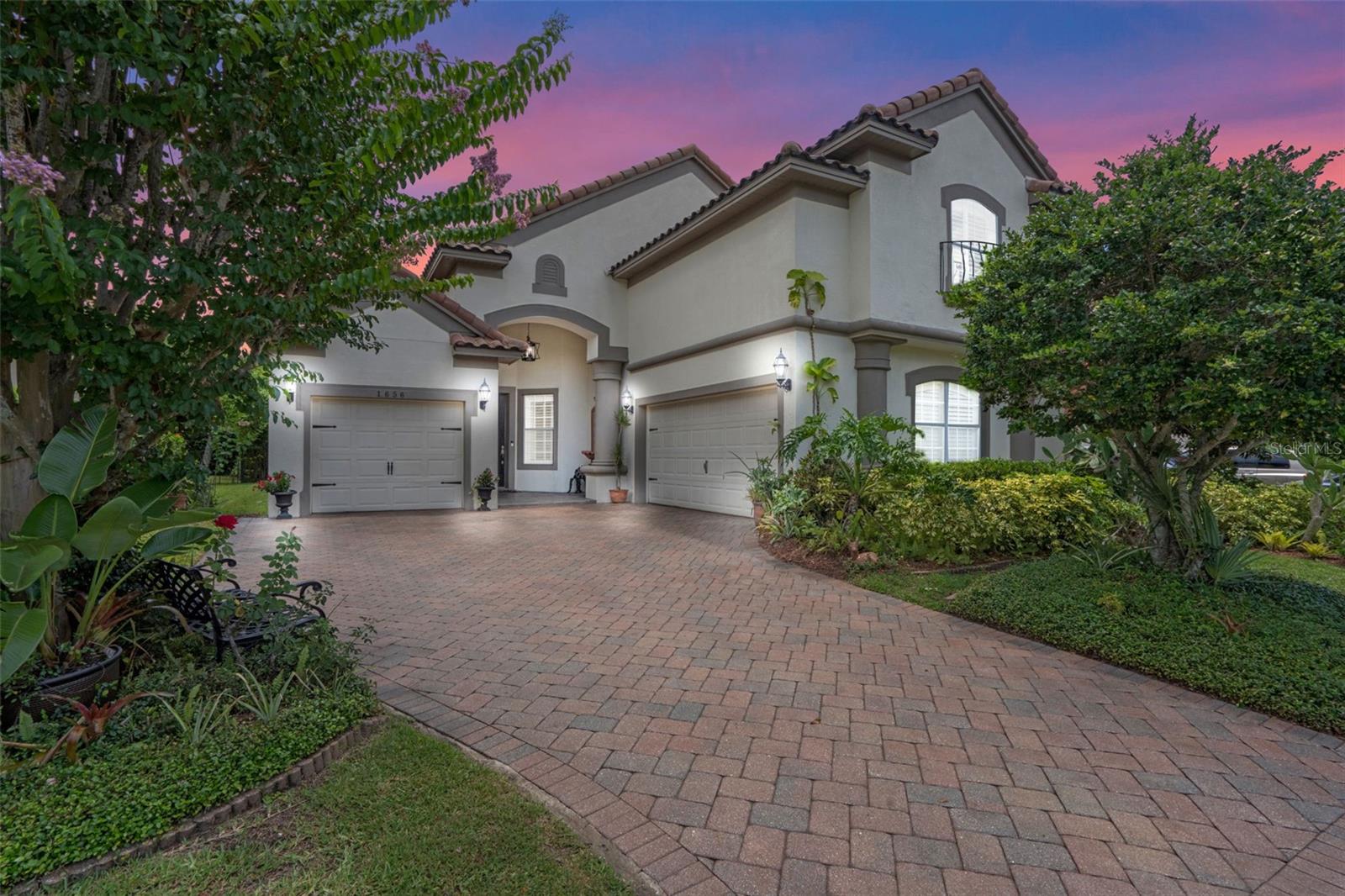 Tucked inside one of Windermere’s most sought-after gated communities, this beautifully landscaped luxury residence combines refined interior touches with tranquil outdoor living. With every bedroom featuring its own private ensuite, this layout offers both comfort and flexibility—whether you need guest space, office space, or room to stretch out. One of the highlights? The expansive 27-foot primary bedroom, offering a rare amount of space and comfort rarely found in similar homes. From the moment you arrive, you’ll notice the classic curb appeal—brick-paved driveway, barrel tile roof, and a lush landscape framing the welcoming entry. Inside, a bright open-concept layout offers seamless flow from the formal dining area to the casual breakfast nook and spacious living room. Custom drapes, ceramic tile flooring in the main areas, and laminate wood floors in the bedrooms give the home a polished, cohesive feel. The kitchen is a true highlight—appointed with granite countertops, stainless steel appliances, a closet pantry, and a breakfast bar ideal for casual dining. A window over the stove brings in natural light, while a nearby laundry room offers added convenience. Pocketing sliding glass doors lead to a screened-in patio that blends indoor comfort with outdoor charm. Beyond the patio, the fully fenced yard is a private retreat featuring lush greenery, a thoughtfully designed brick-paved path and patio, and a tucked-away fountain surrounded by sculpted shrubs. Whether you're sipping morning coffee, hosting guests, or enjoying some quiet time, this backyard is both functional and picturesque. The downstairs primary suite is generously sized and includes a walk-in closet and a well-designed ensuite bathroom featuring double vanities, a large soaking tub, private water closet and a walk-in shower. A second downstairs bedroom also includes a private ensuite—ideal for guests or multi-generational needs. Upstairs, a massive bonus room offers flexibility as a third bedroom, media room, or office—with its own full bathroom and three closets for ample storage. The home also includes a single-car garage and a separate two-car garage, allowing for multiple vehicles or additional storage. Just a short stroll from your front door, you’ll find the Belmere clubhouse—complete with an events space, a fitness center, tennis courts, basketball court, community pool, and playground. Belmere Village is known for its serene lakes, scenic walking paths, and strong sense of community—all behind secure gated access. Windermere is prized for its peaceful charm and proximity to it all. Belmere offers quick access to major highways, top-rated schools, and world-renowned attractions like Walt Disney World—just 20 minutes away. Local shopping and dining are just around the corner, and the nearby Winter Garden Village and Dr. Phillips areas provide even more options. Zoned for high-performing public schools and near elite private options like Windermere Prep, this location blends convenience with prestige. Additional notable features: 6-year-old A/C, decorative built-ins and soaring ceilings. If you're seeking an elegant home in a premier community with generous space, timeless finishes, and convenient access to the best of Central Florida—this is it.