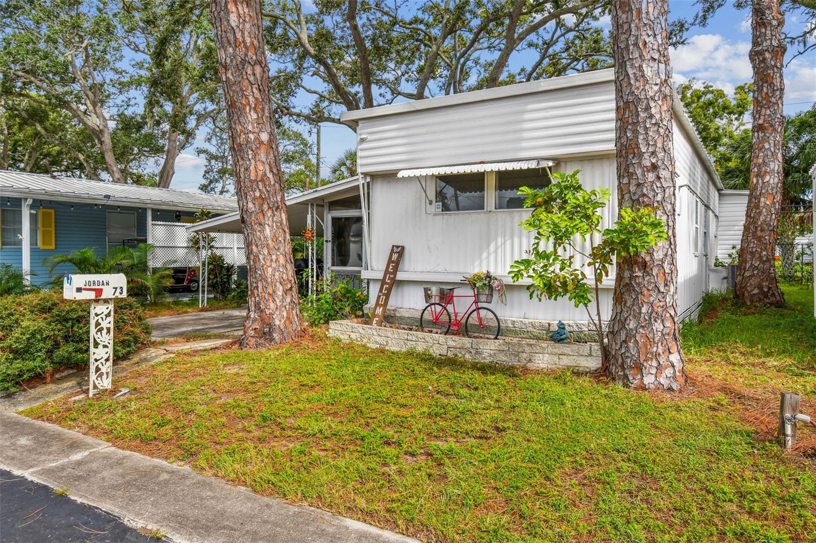 AFFORDABLE FLORIDA LIVING!!! This unit is FULLY FURNISHED and features 2 full bedrooms and 1 1/2 Bathrooms. Plenty of potential with the Large Florida room full of windows perfect for entertaing guest or relaxing in this ample space. Perfectly situated on a lot with no rear neighbors giving you added privacy and greenspace. The large carport can hold 2 vehicles and has a great outdoor space to grill and chill as well as 2 storage sheds for extra stroage. Inside you will find an open floorplan with an eat in space in the kitchen, built in shelving and and access to the Laundry room just off the hallway. The full bathroom with large tub and shower combo is large and has plenty of storage. The primary bedroom host an ensuite bathroom and a walk-in closet. Melody Gardens is an age-qualified park that is conviently tucked away that boasts community pool, hottub, shuffleboard, golf cart friendly and lots of activities for its residents. You will enjoy the close proximity to shopping, dining, short drive to our beautiful beaches and so much more. The low HOA of $175 montly includes water,sewer, trash and all the amenties. So don't miss your opportunity to enjoy the relaxed Florida Lifestyle in this affordable furnished home.